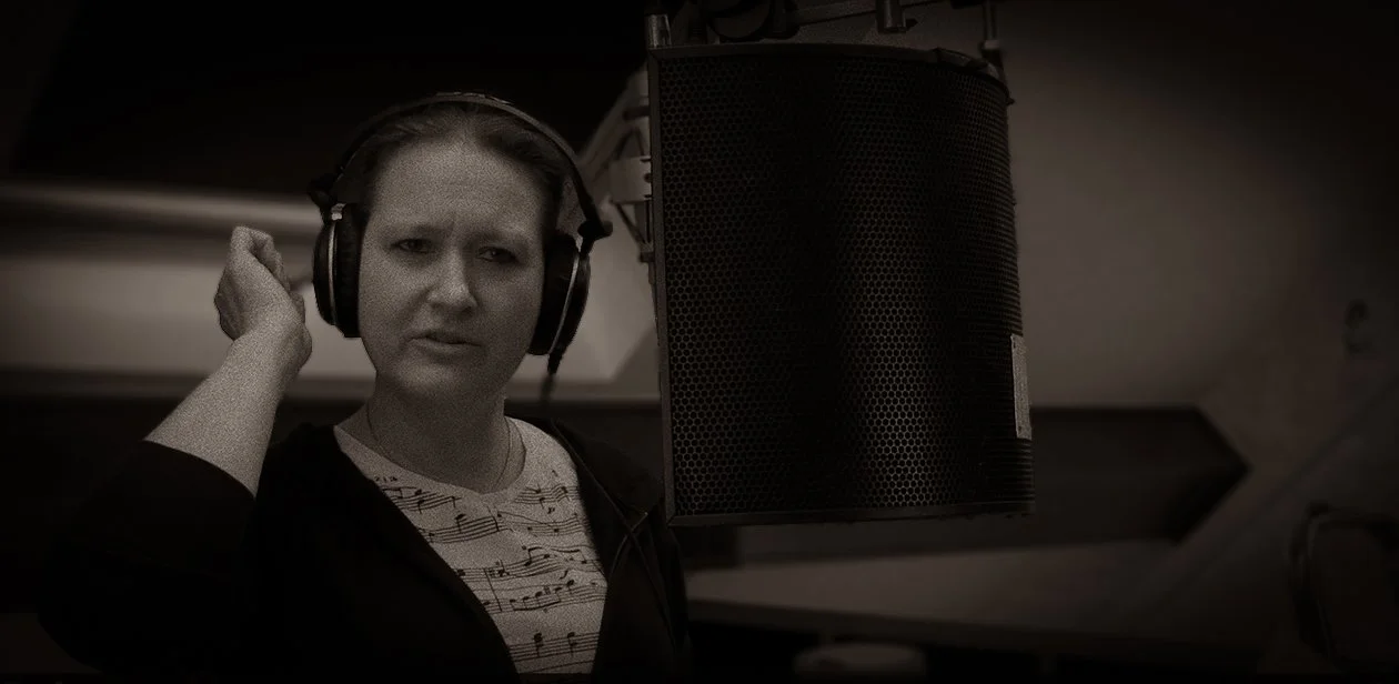 Vrouw in een opnamestudio met koptelefoon voor een microfoon