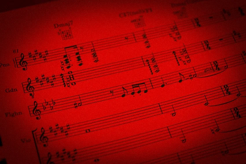 Muziekblad met noten op een rode achtergrond.
