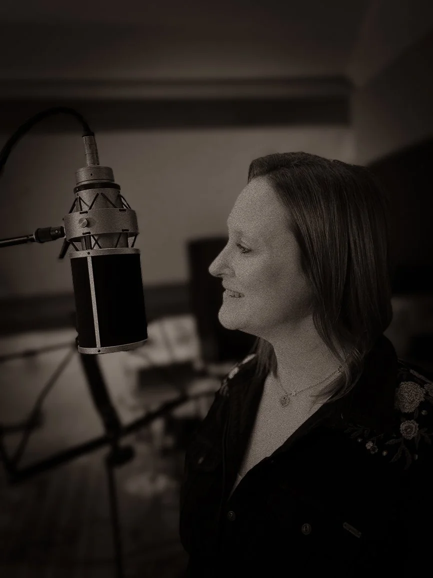 Een vrouw zingt of spreekt in een professionele microfoon in een opnamestudio.