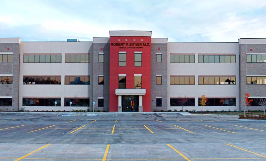 Exterior view of the Robert F. Bitner M.D. Medical Office Building with an empty parking lot and a clear sky.