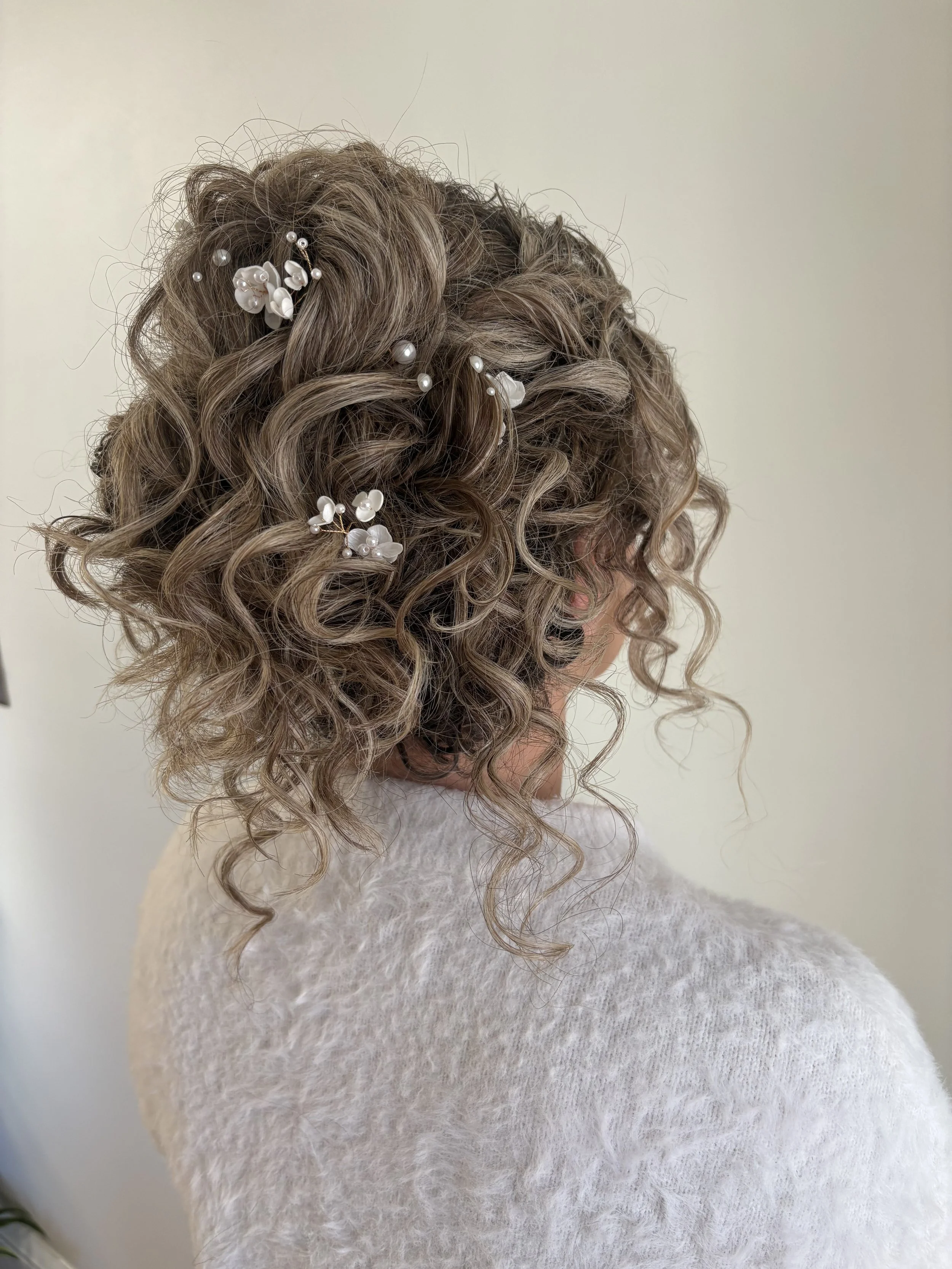 Curly bridal updo with floral and pearl accents, bridal hairstyle by Do’s & Dye”