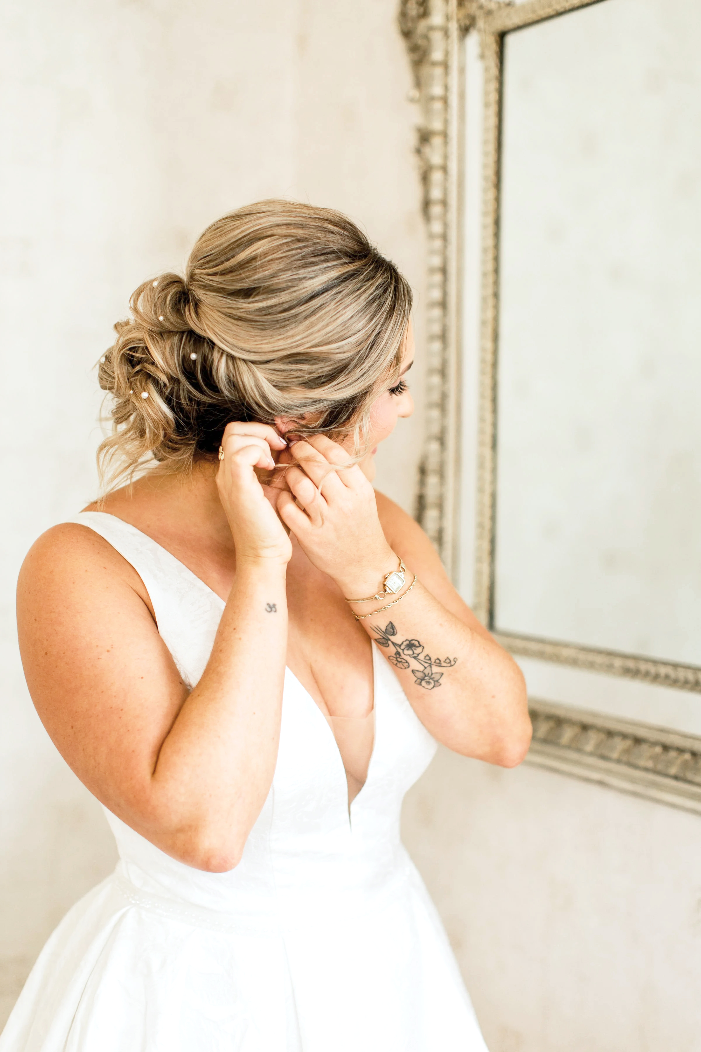 Bride putting on earrings in a white gown, captured during quiet pre-ceremony moments in West Hartford