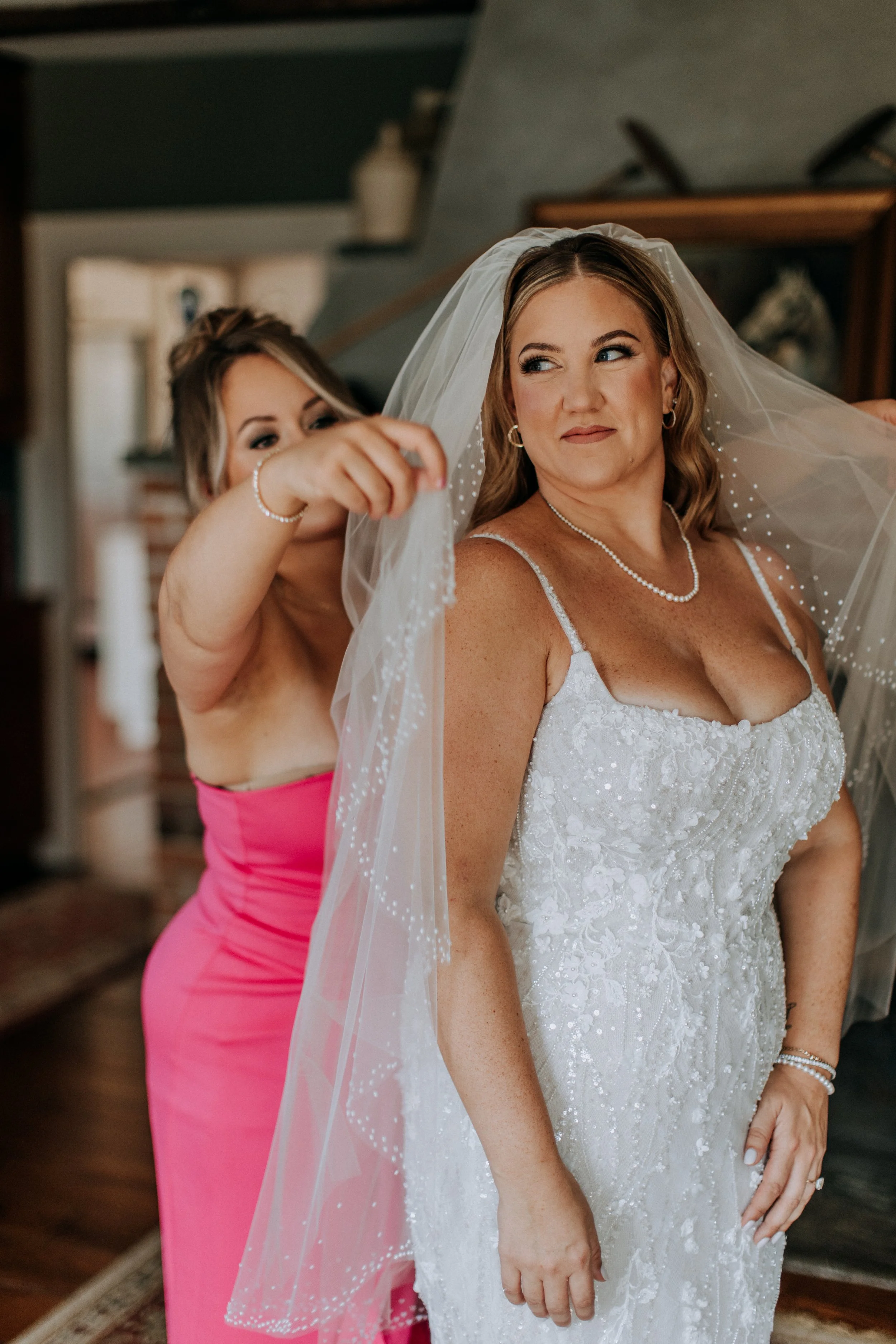 Bride getting ready as a bridesmaid adjusts her veil during wedding day content creation