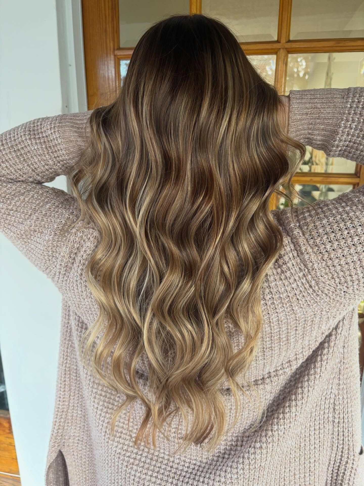 Back view of long,  warm, dimensional blonde waves with soft highlights and natural movement.