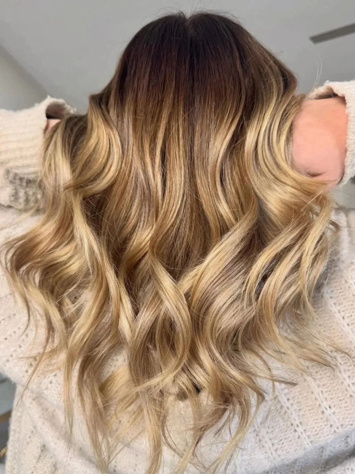 Soft, dimensional blonde with darker roots and loose, lived-in waves, created at Do’s & Dye Salon