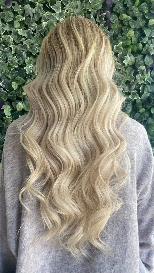 Long blonde hair with loose curls, professional color and styling at Do’s & Dye Salon in West Hartford