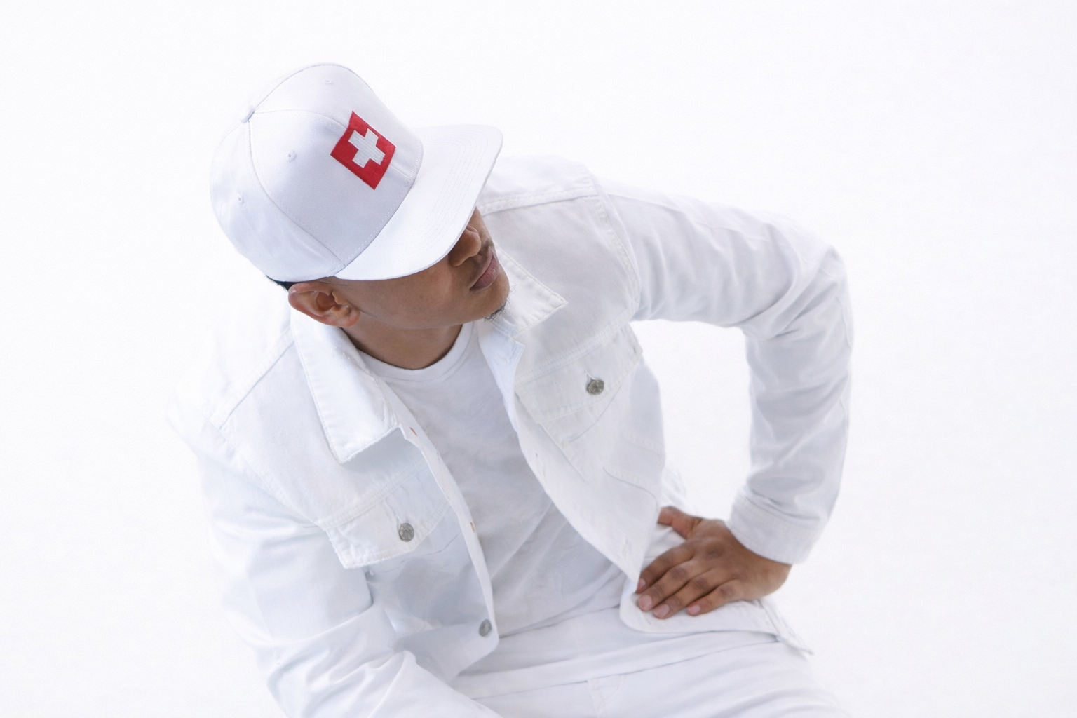 A dynamic angled shot of CV$H leaning forward in an all-white fit, captured mid-motion with a composed, deliberate posture that adds energy and movement to the frame.