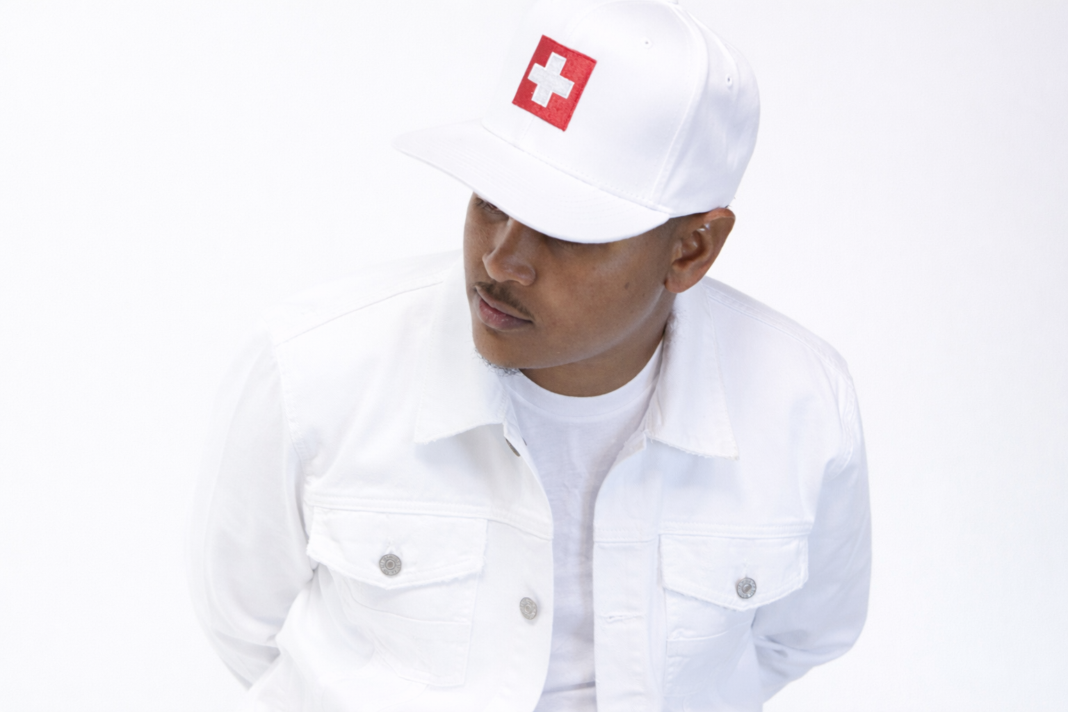 Close-up studio shot of CV$H in a white outfit and cap with face partially shadowed