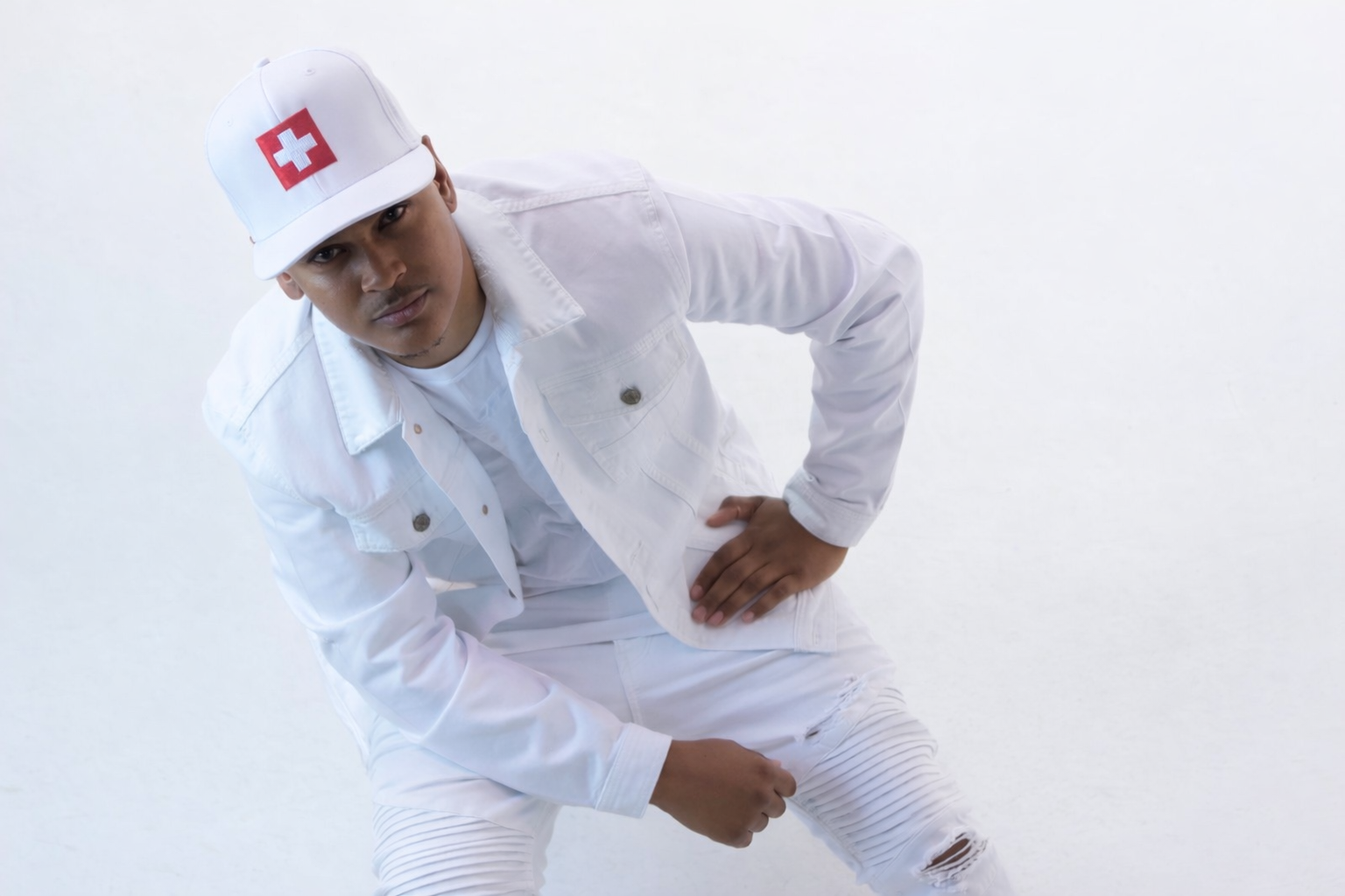 CV$H wearing an all-white outfit and cap in an official studio press photo