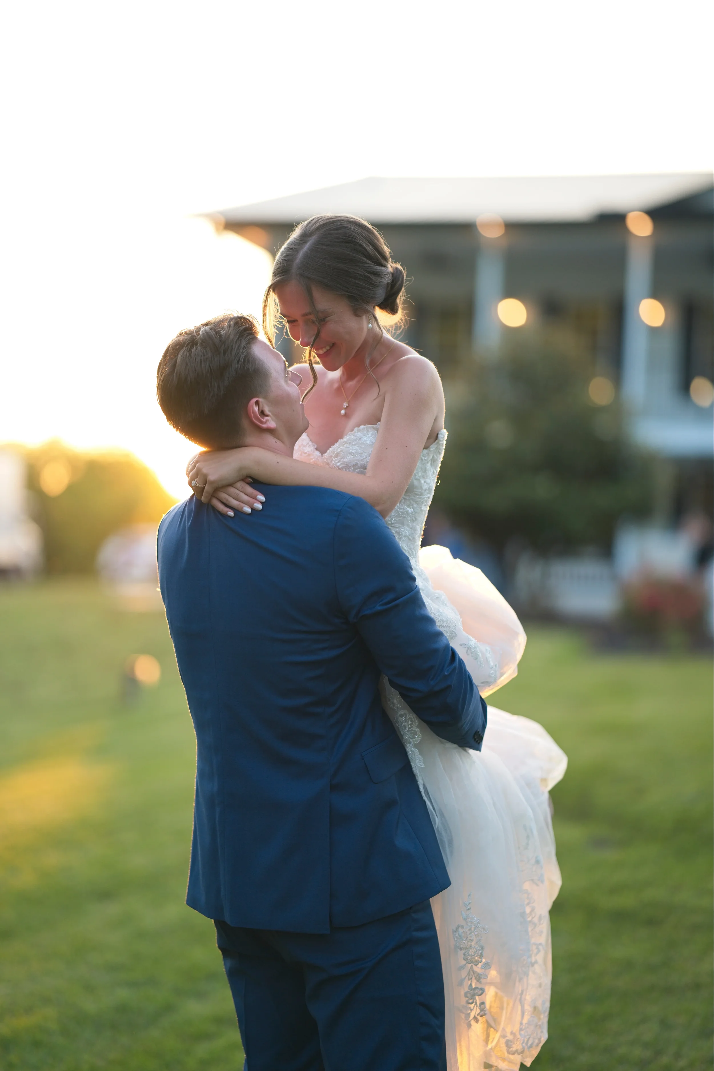 Husband holding up wife with the sunset behind them