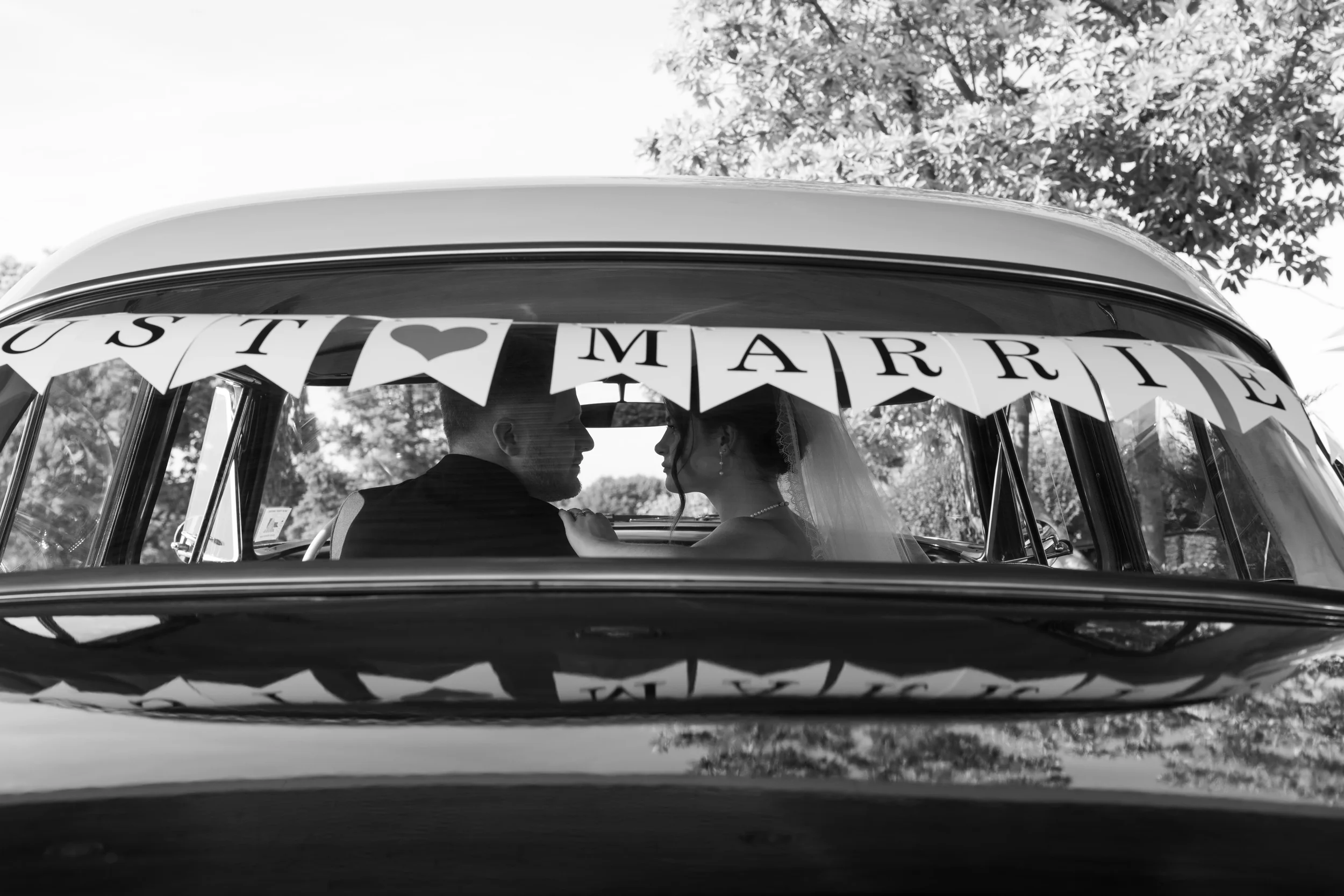 Husband and wife looking at eachother through back windows of car
