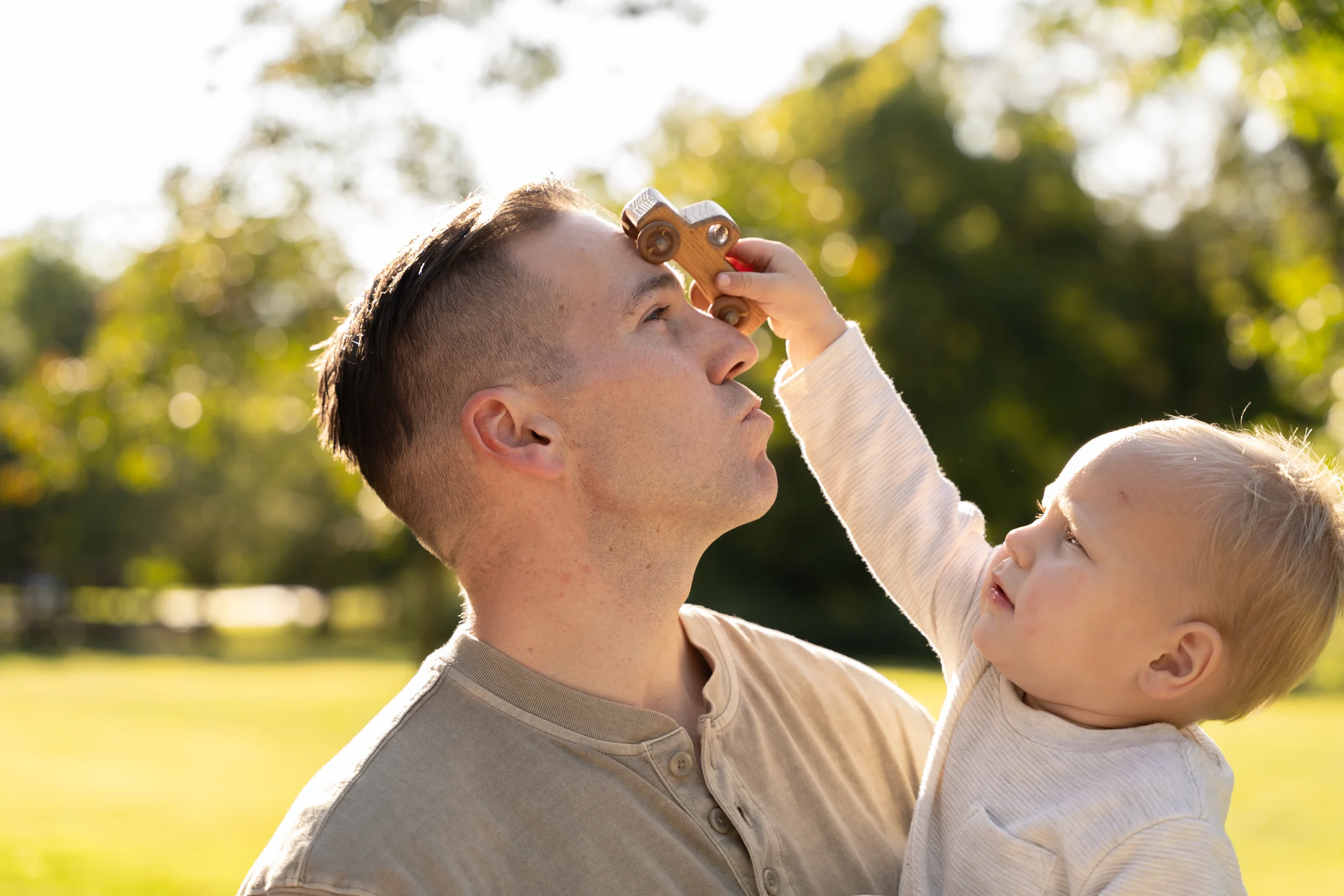 Son playing with wooden truck on fathers face 