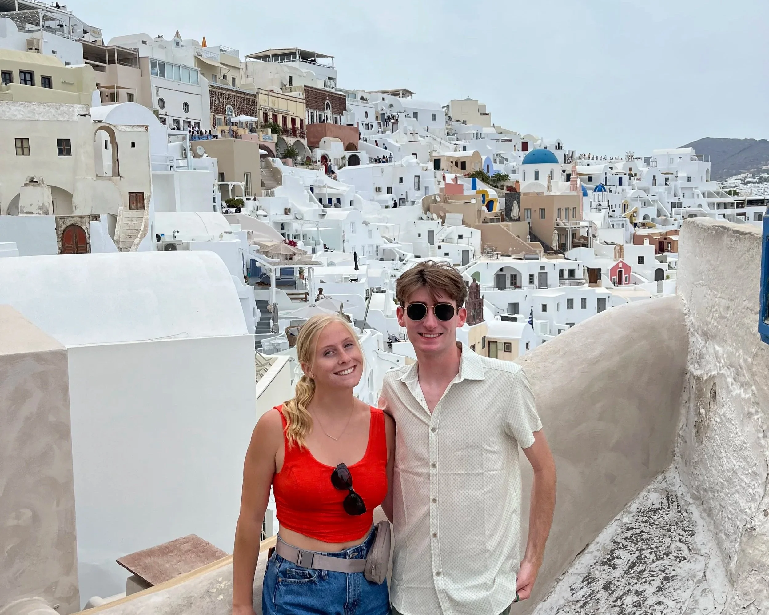 Joseph and his sister posing in front of views of Oia, Santorini