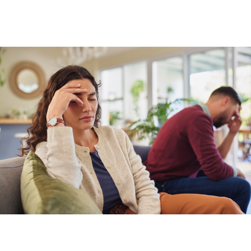 Young professional couple in a clean, organized home looking exhausted and disconnected, depicting the transition from romantic partners to roommates with a mortgage