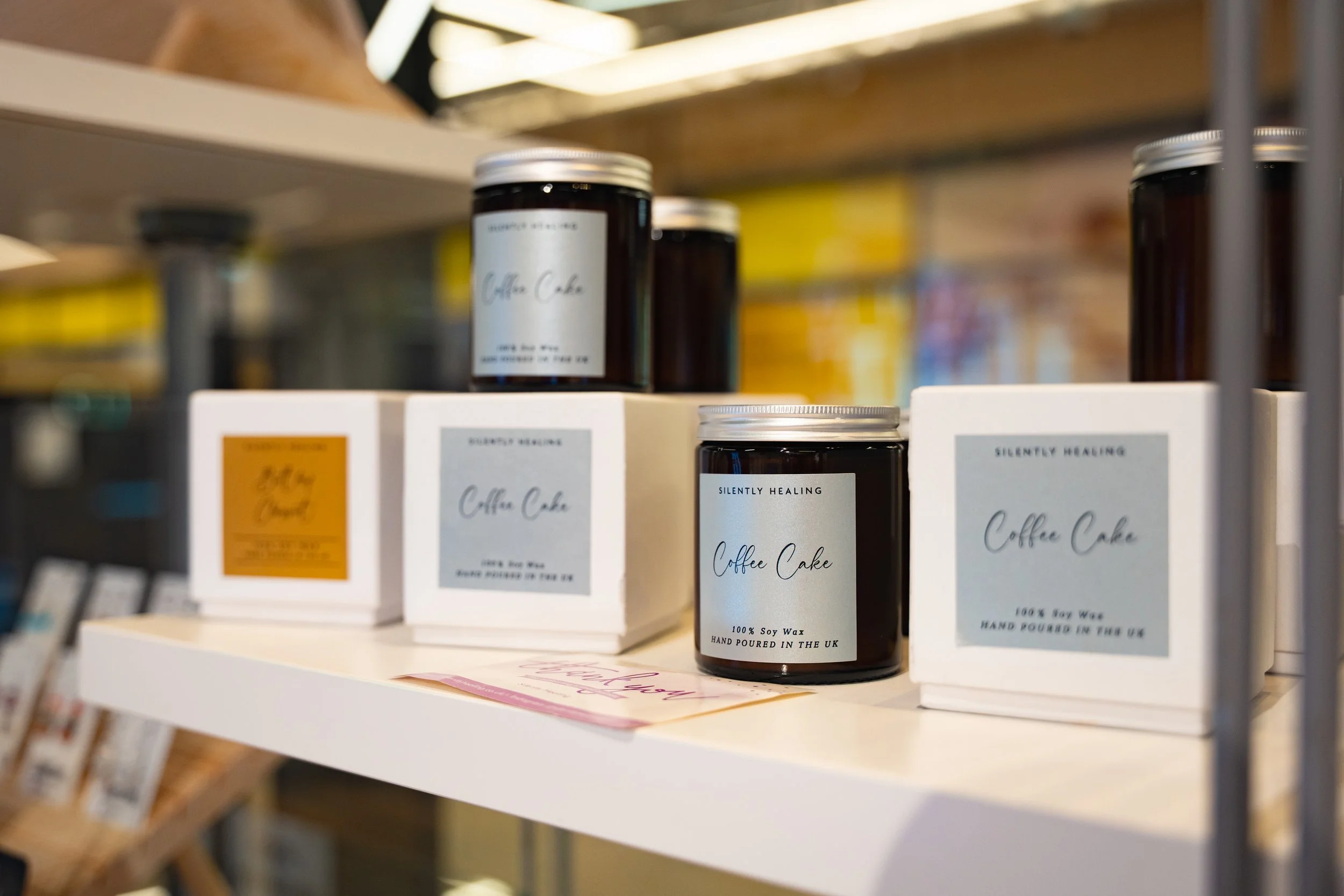 Candle jars and boxes labeled 'Coffee Cake' on a store shelf.