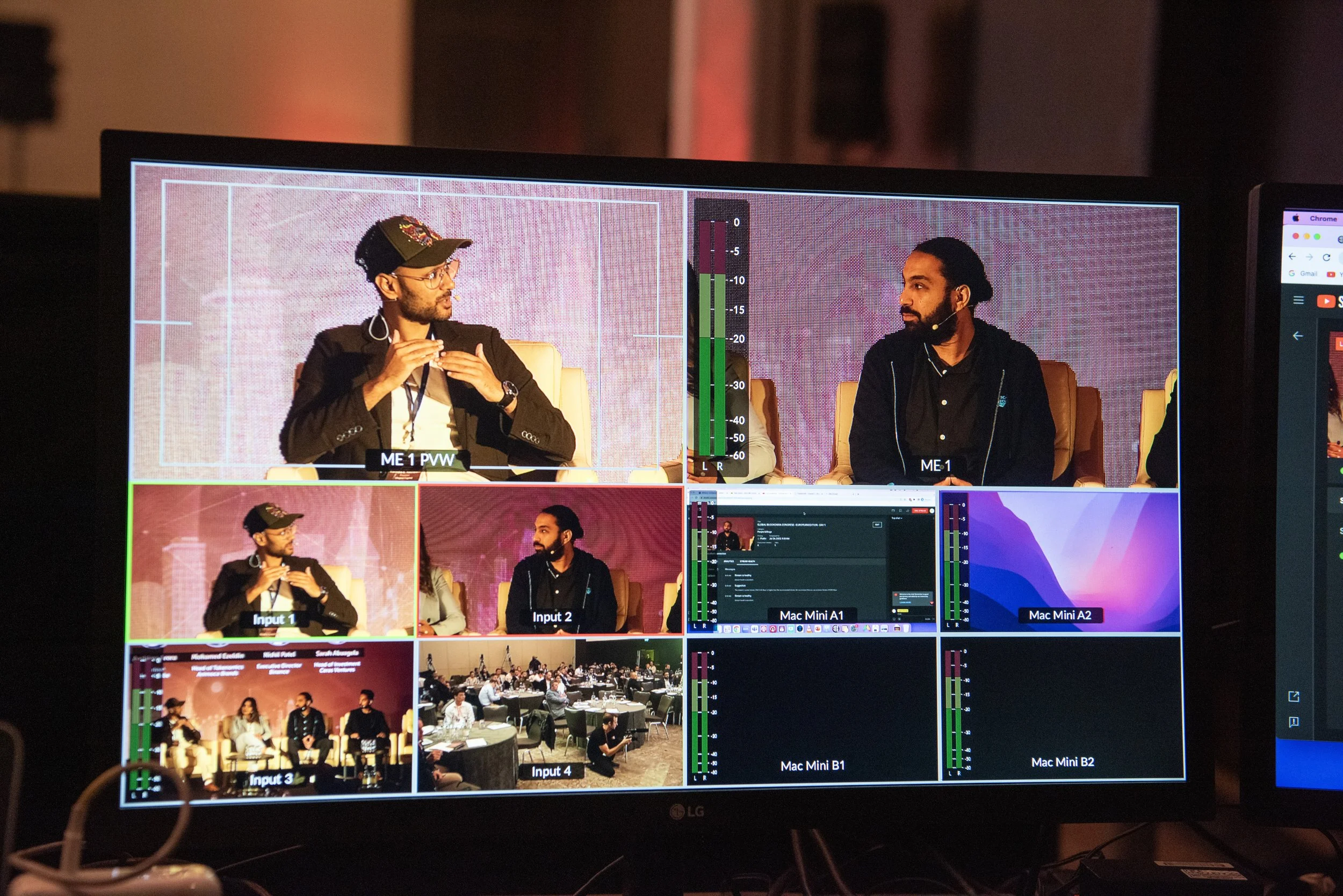 A multi-camera video switcher monitor displaying a panel discussion with several people seated on stage. Multiple video feeds, including close-ups of speakers, audience, and technical screens, are visible on the monitor.