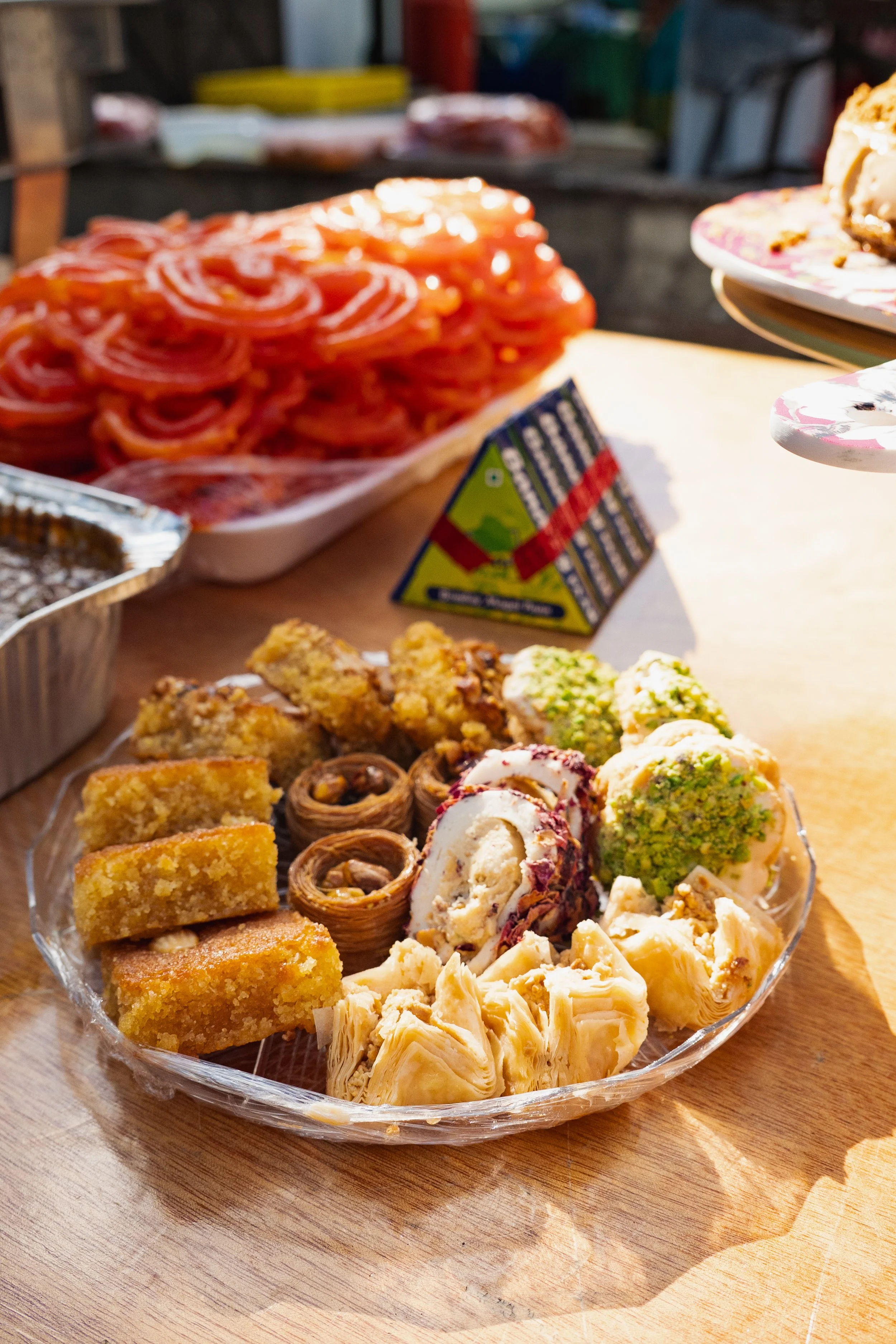 Dessert platter with various sweets, including cannoli and pistachio-flavored confections, on a wooden table.