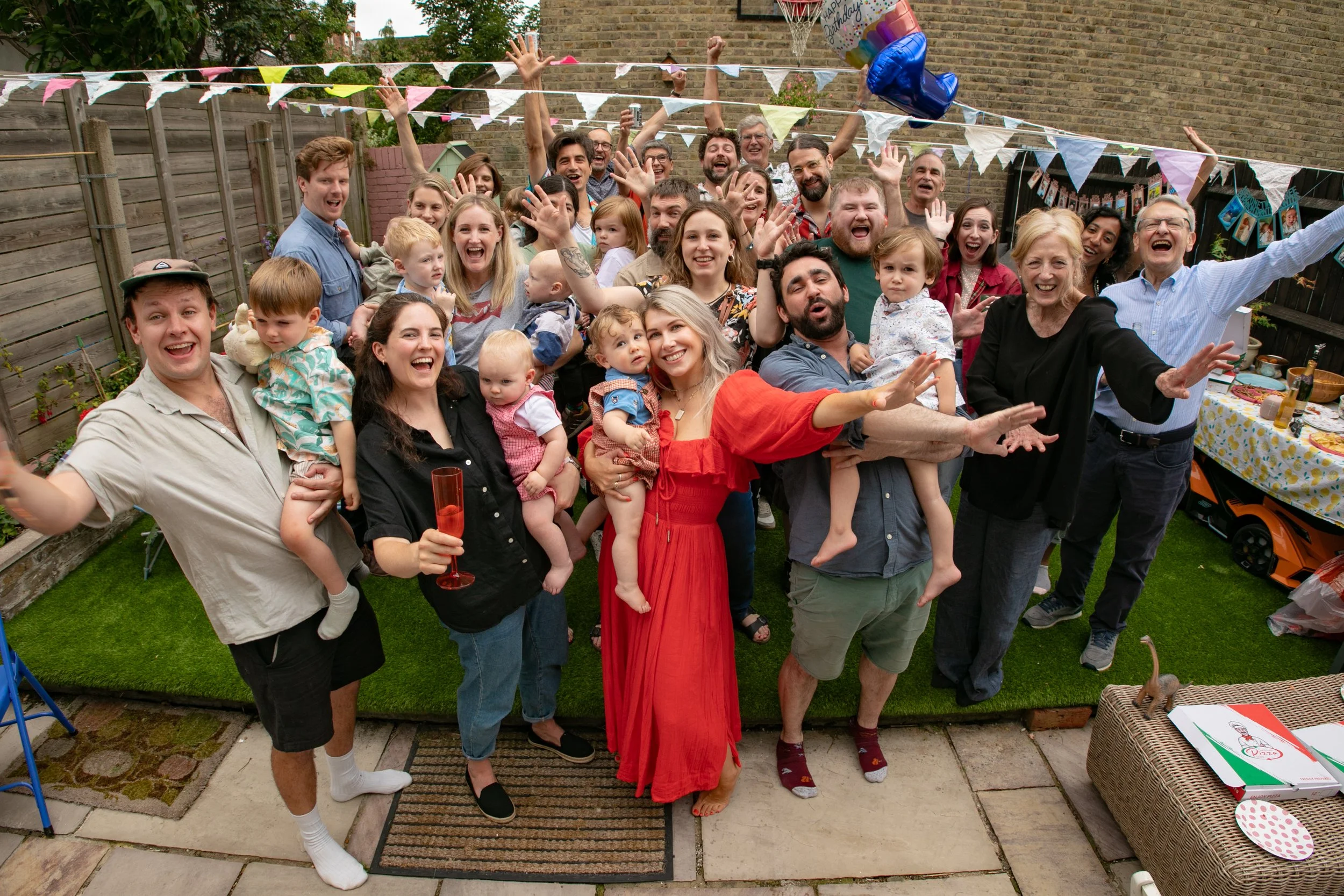 Group of people celebrating at a backyard birthday party with decorations and balloons.