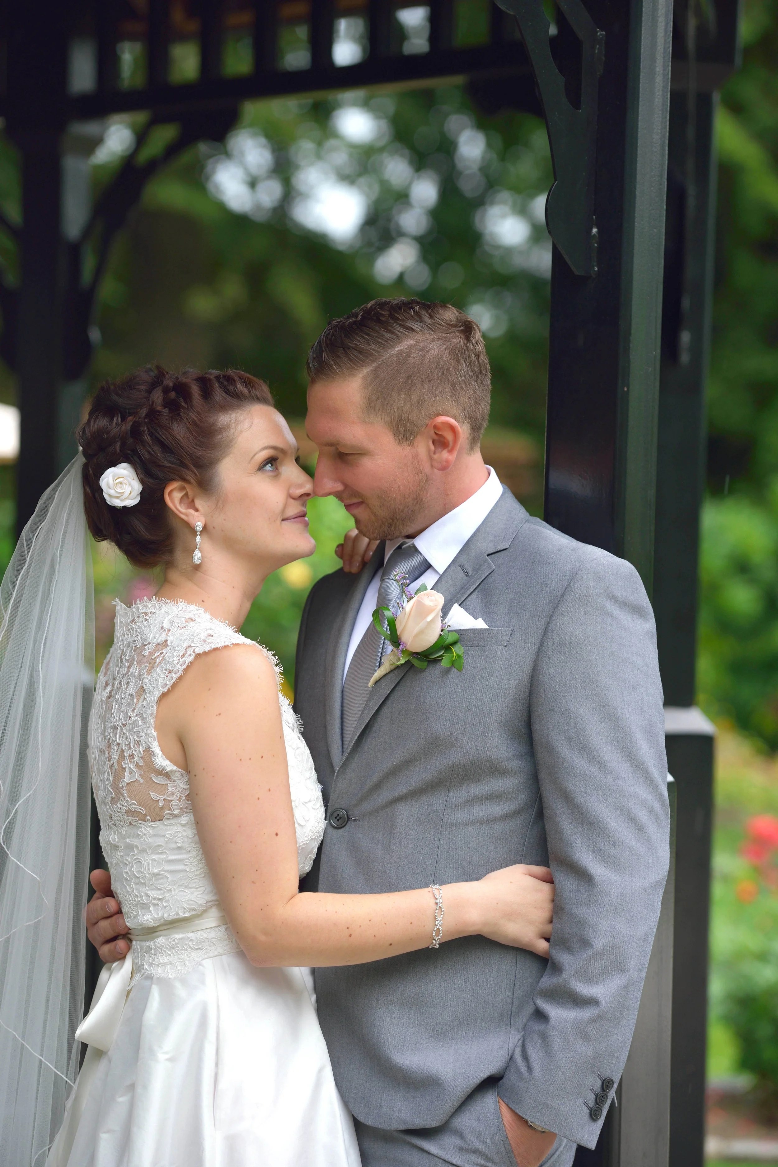A bride and groom gazing into each other's eyes during their wedding, with greenery in the background.