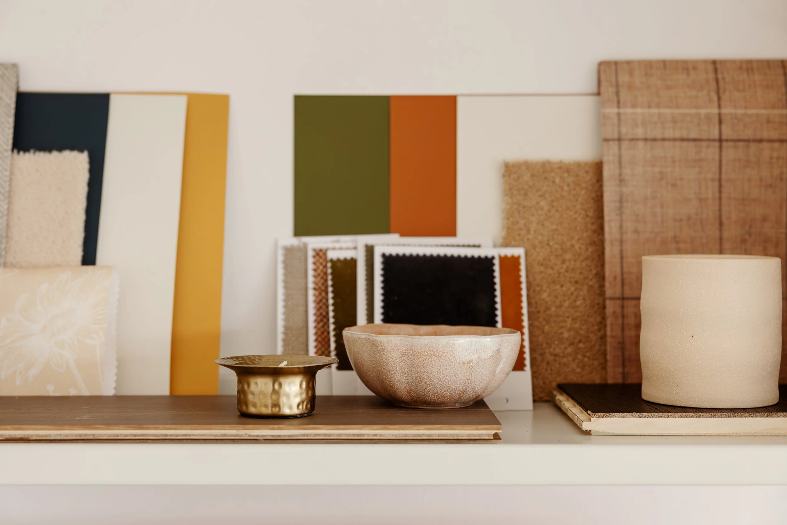 Interior styling detail showing colour palette samples, materials and decorative objects arranged on a shelf.