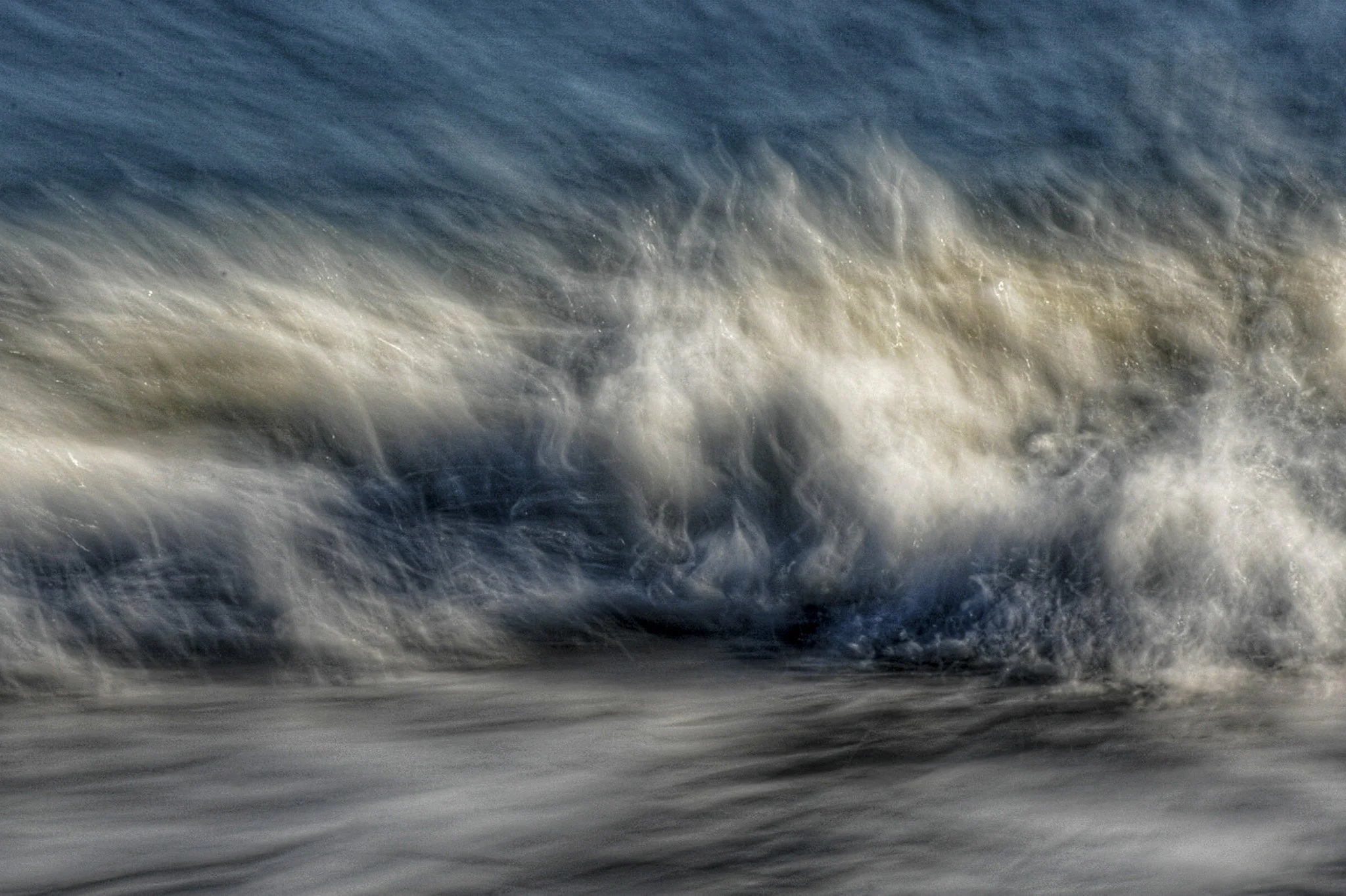 Close-up of ocean waves crashing and swirling, showing white foam and dark water.