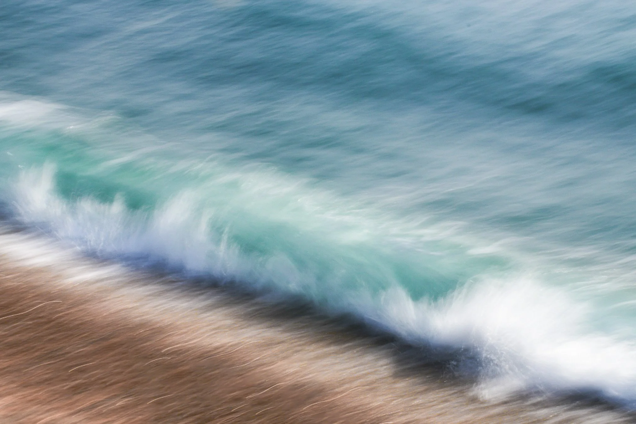 Abstract of ocean waves crashing onto a sandy beach.