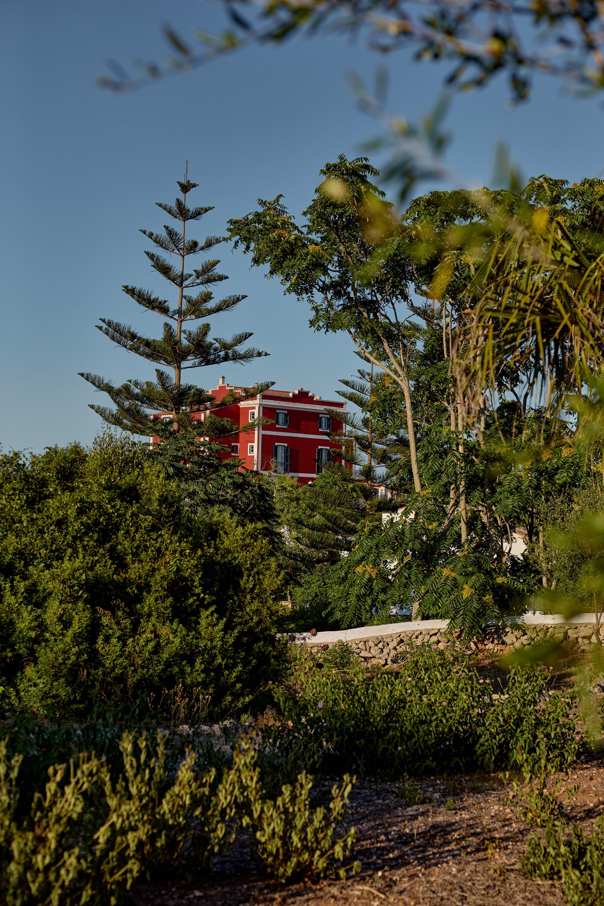 Edificio rojo en medio de árboles verdes con cielo despejado.