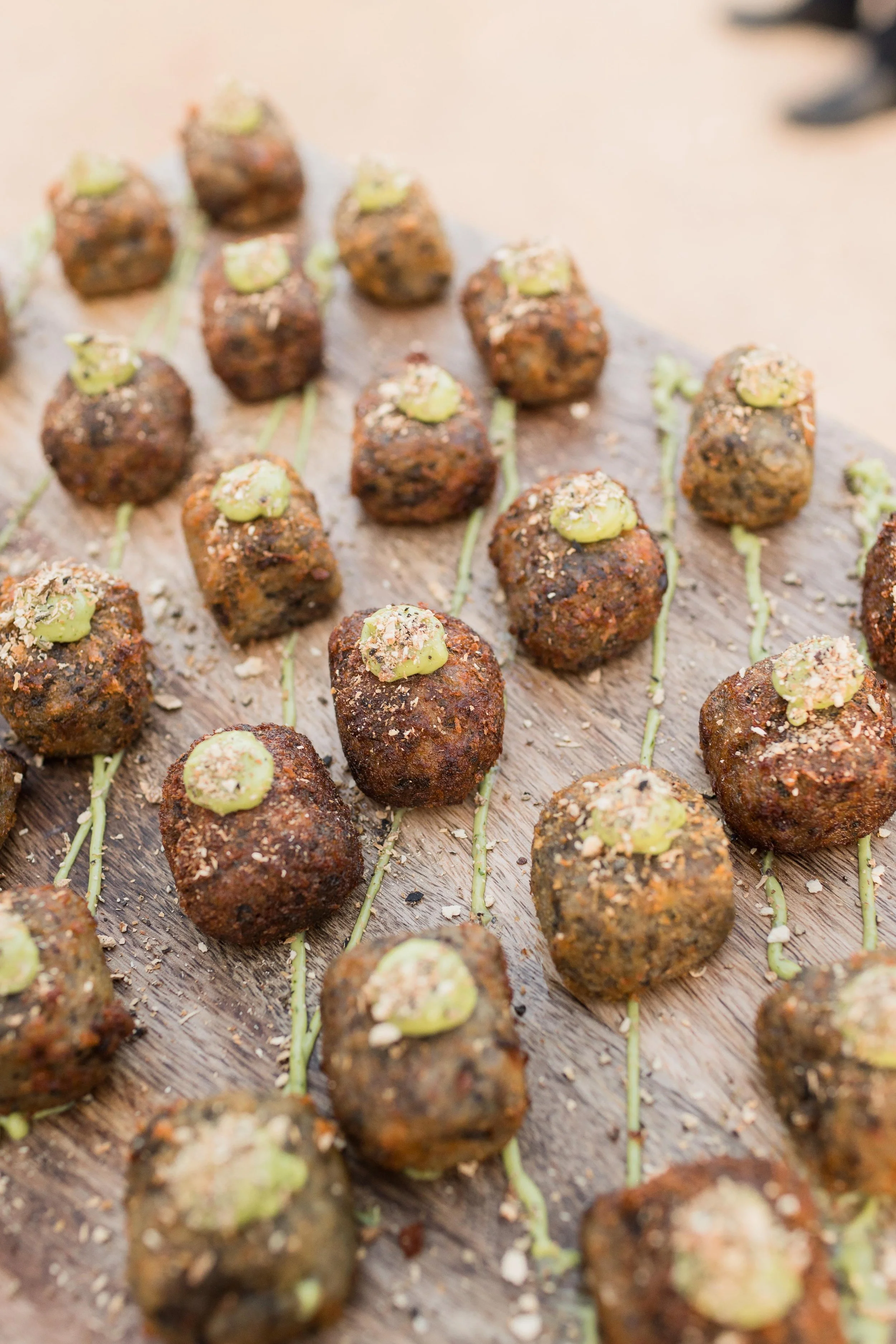 Albóndigas crujientes con un toque de salsa verde y cebolla, servidas sobre una tabla de madera.
