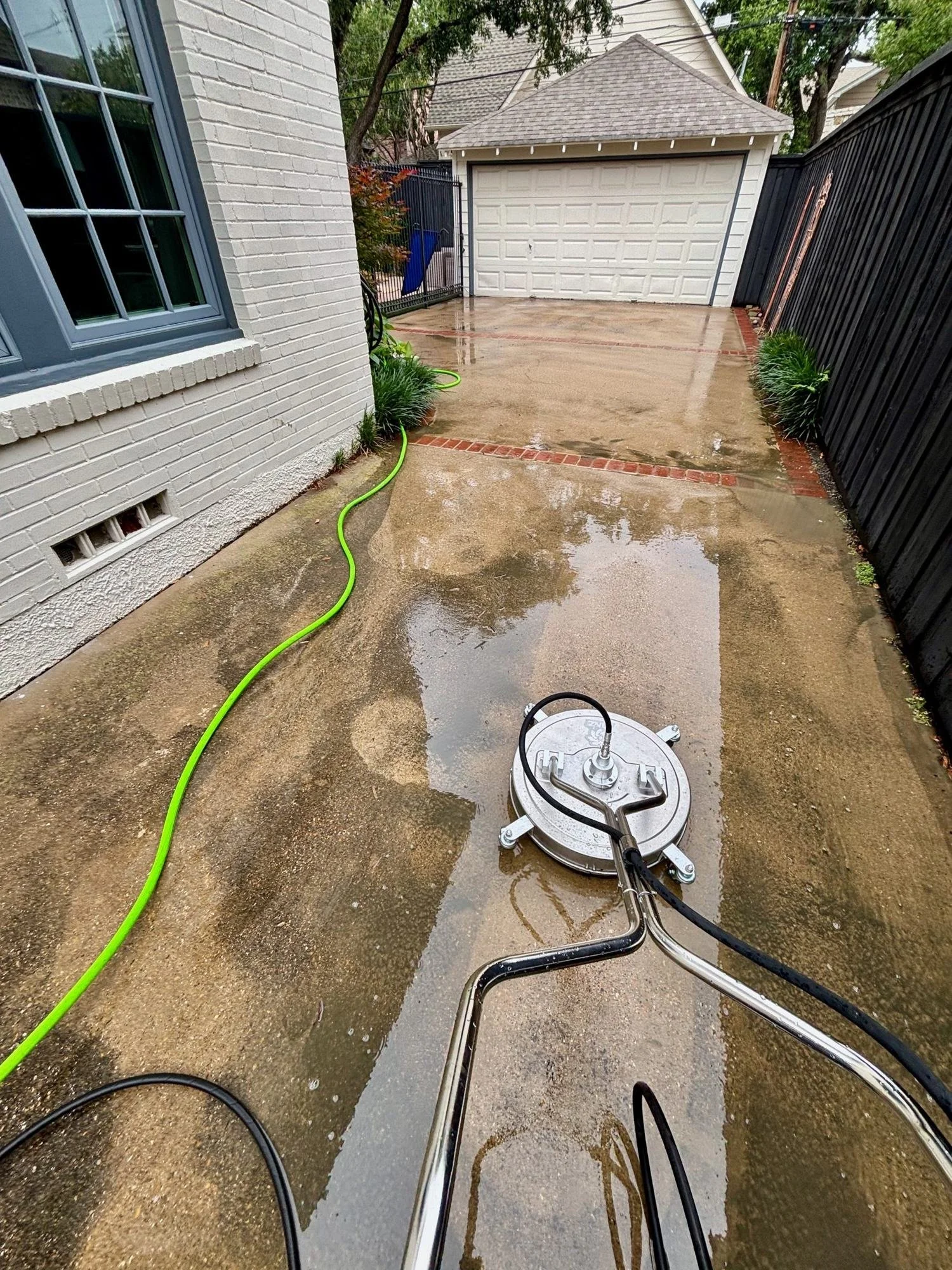 Rotary surface cleaner pressure washing a concrete driveway in University Park, Dallas