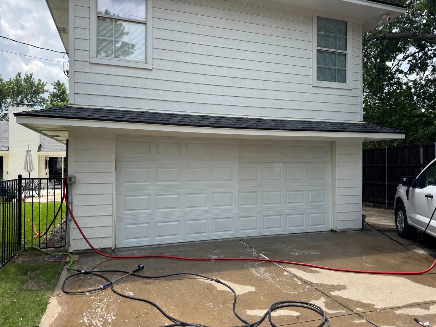 Soft washing the painted siding of a two-story Dallas home with low-pressure equipment
