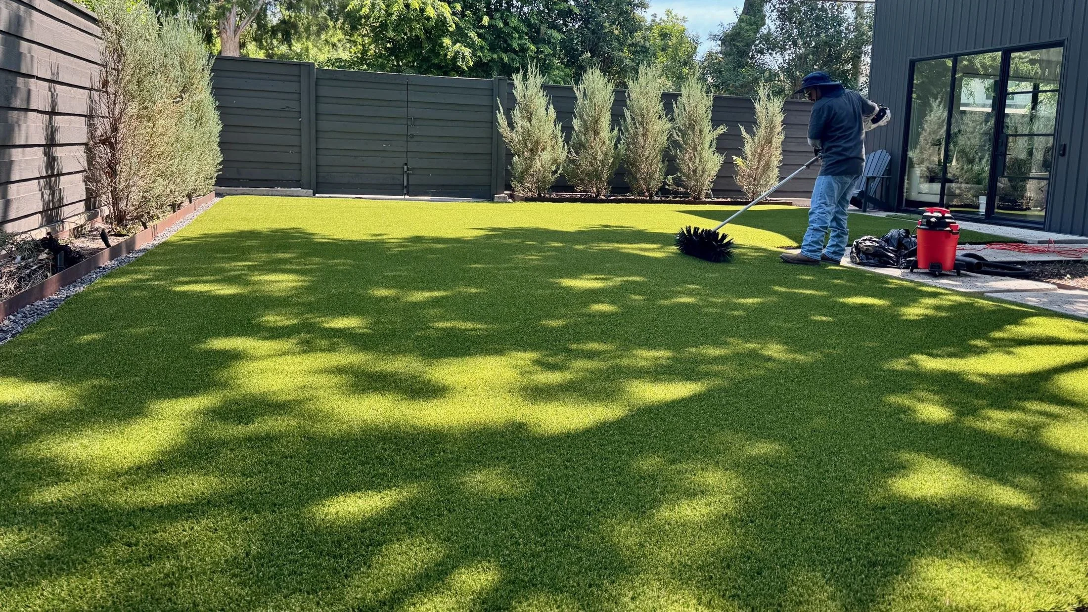 technician deep cleaning artificial turf with a power broom at an East Dallas home