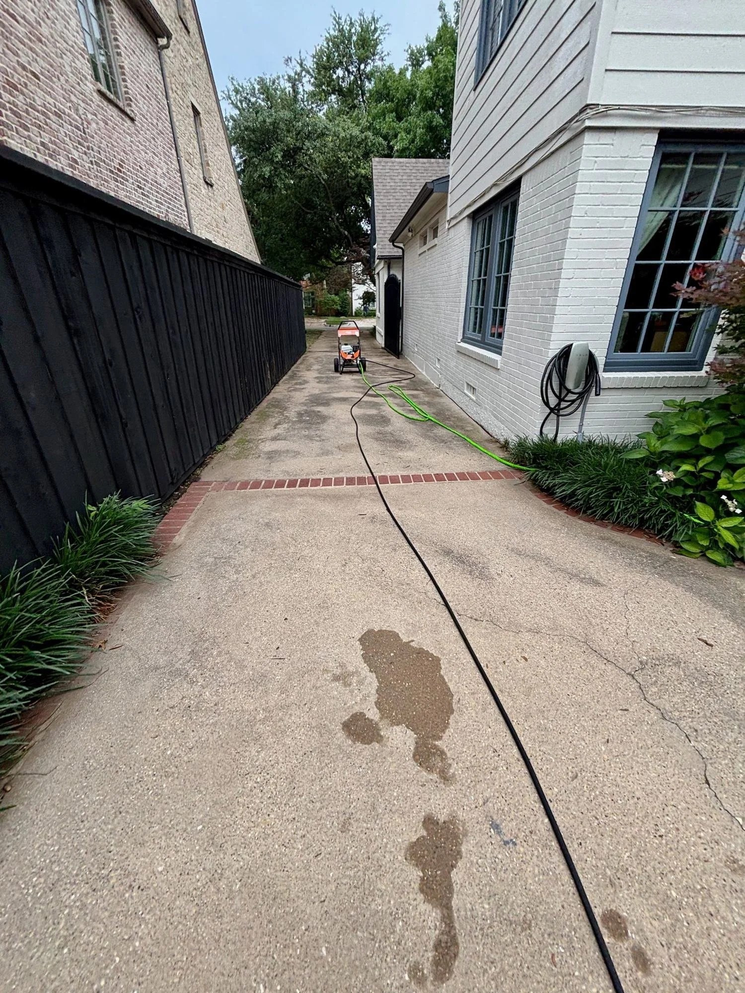 Driveway with oil stains and built-up grime before pressure washing at a University Park home