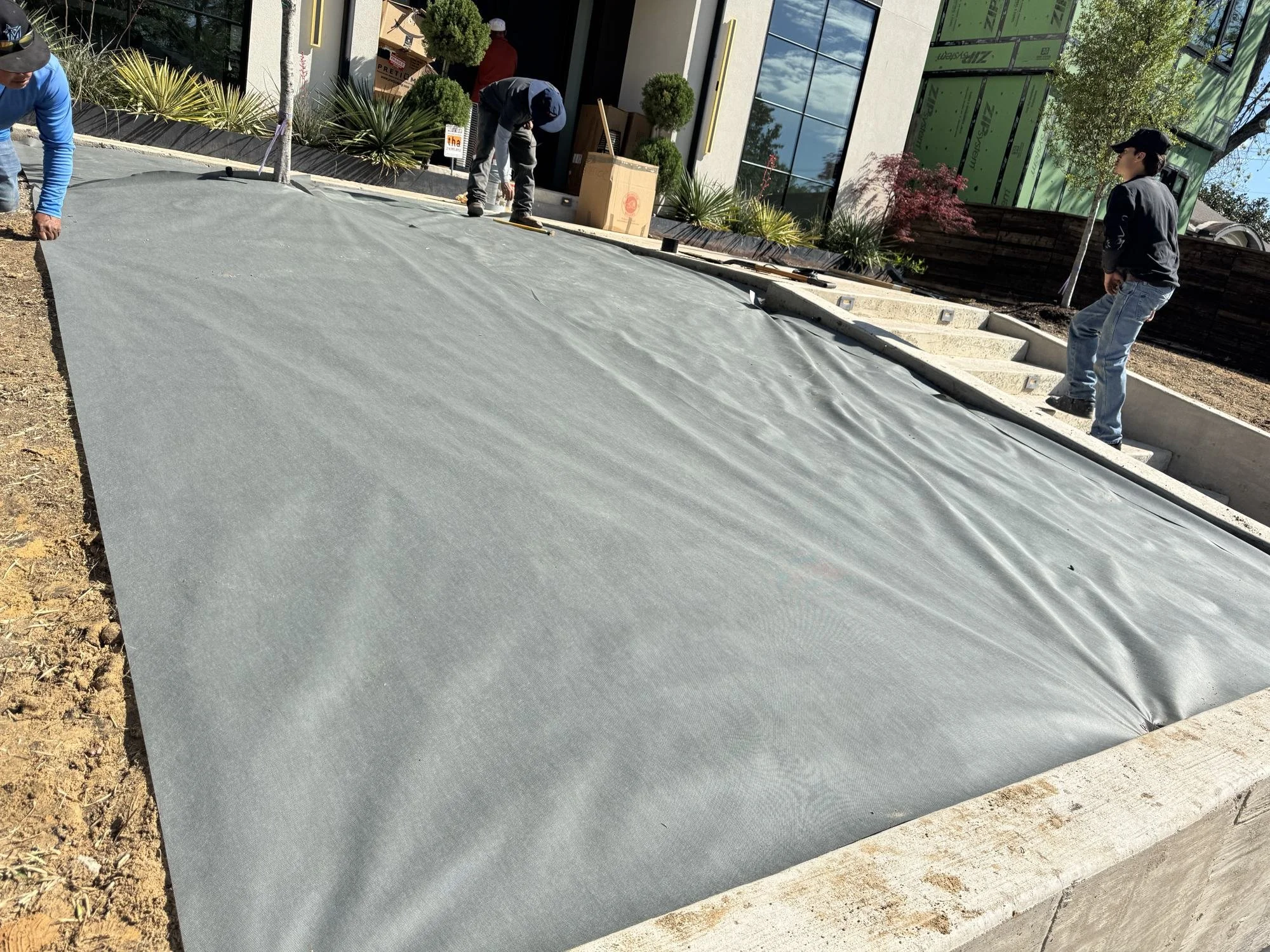 Weed barrier layer installed over a graded base during Spotlite turf installation, Dallas