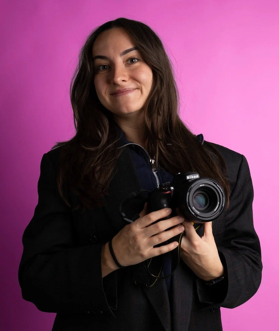 Jonge vrouw met Nikon-camera voor roze achtergrond.