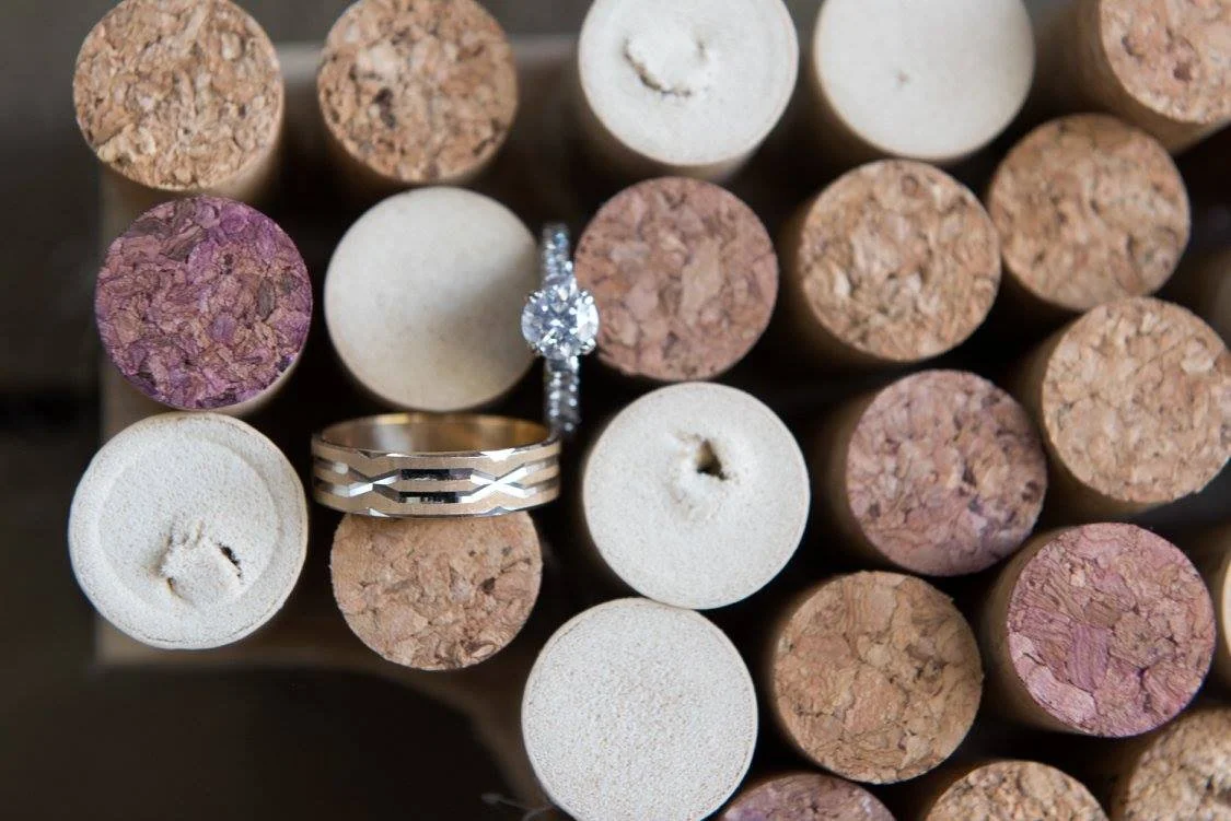 Close-up of a collection of cork and foam push pins, with two rings and an engagement ring with a diamond placed on top.