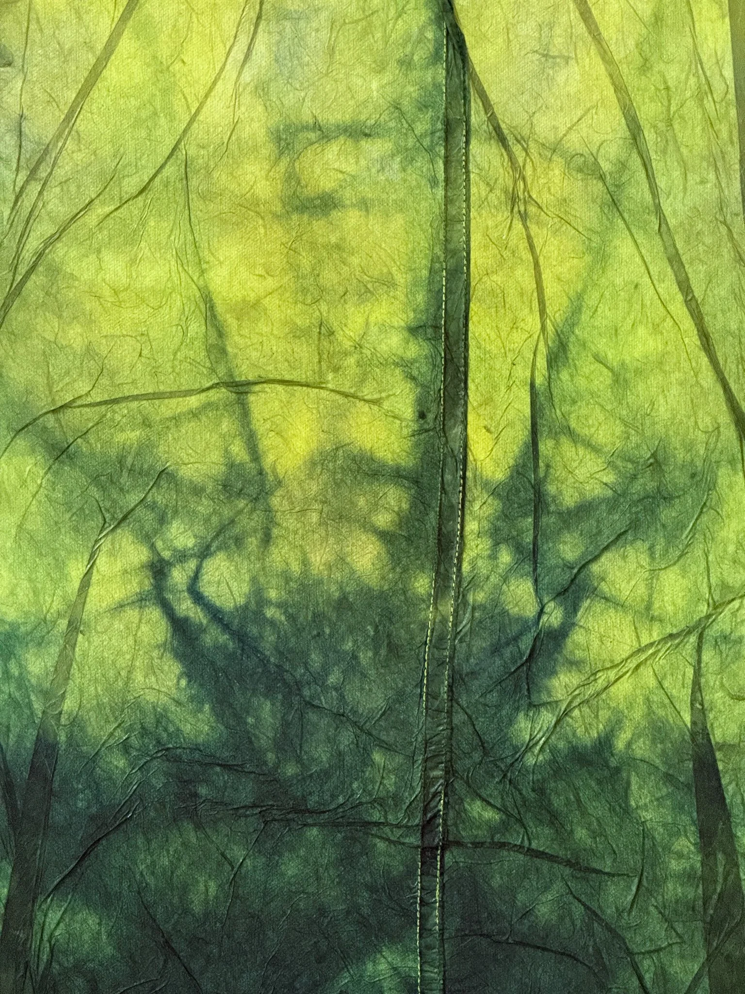 Against All Odds Detail: Abstract green textile surface with layered dye, dark branching marks, and vein-like organic lines.