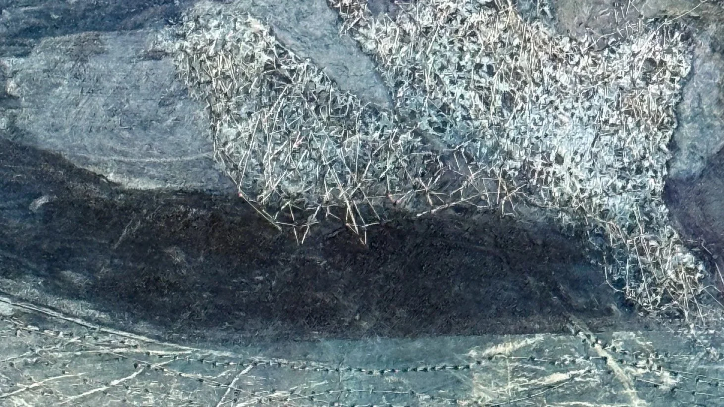 Abstract blue, violet, and silver textile collage with raised stitching, layered texture, and organic landscape-like forms.