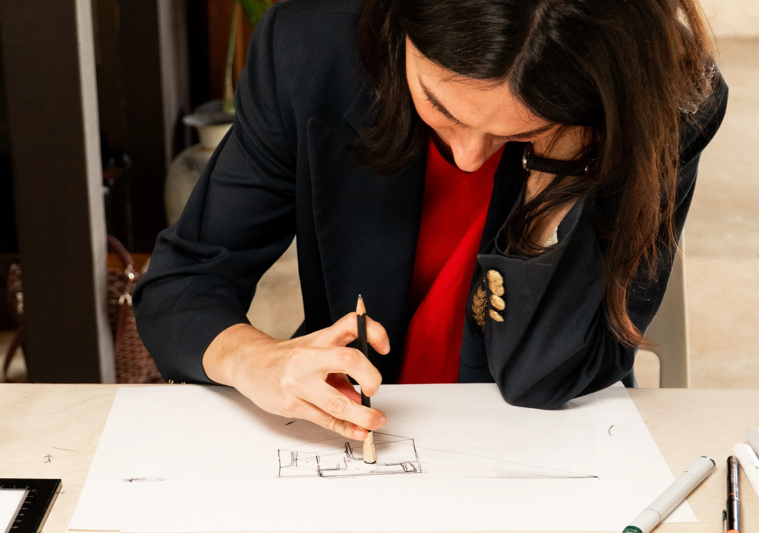 Woman sketching on paper at a desk.