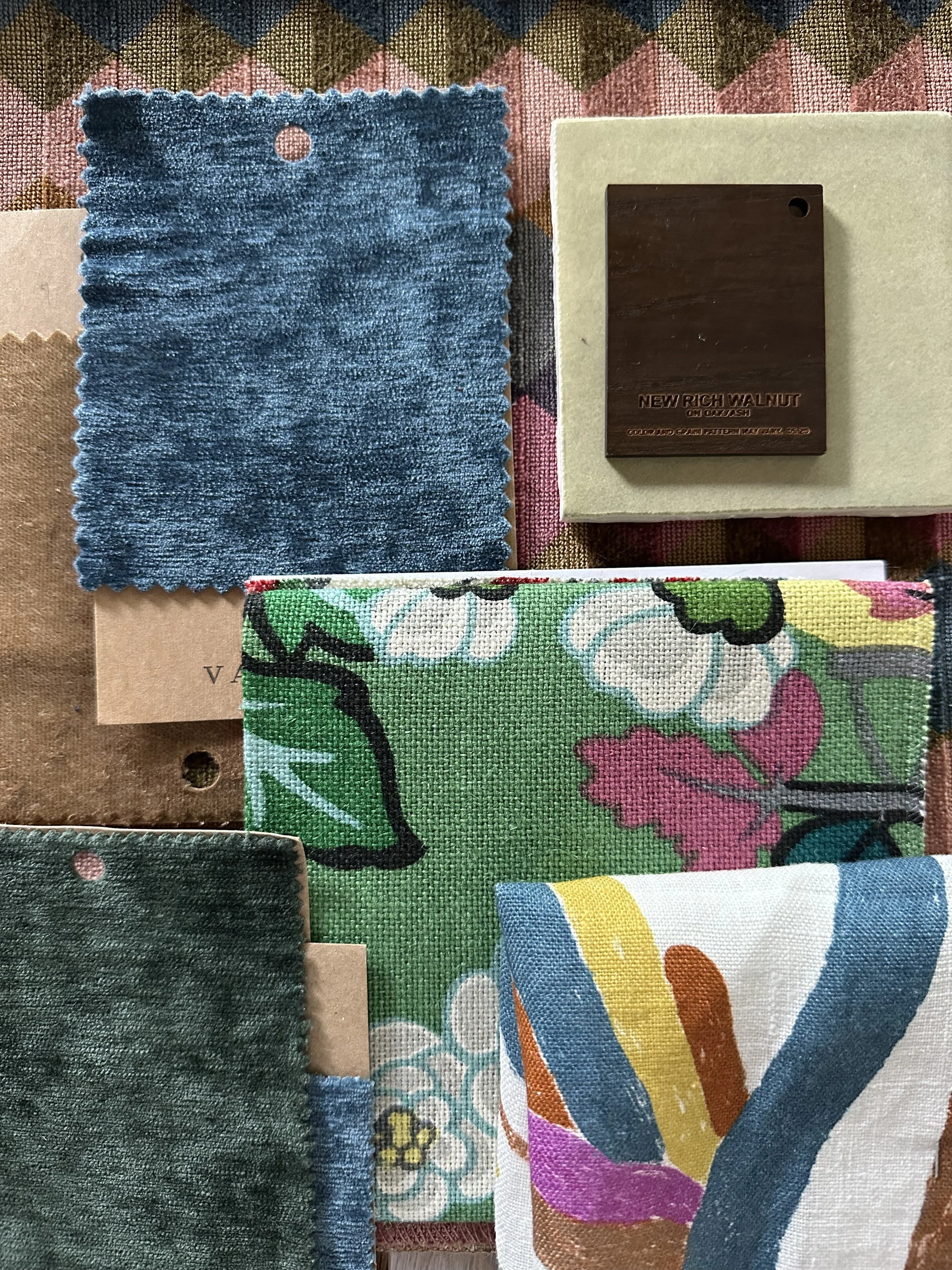 Collection of fabric swatches and a wood stain sample, including a blue velvet fabric, floral patterned fabric, solid green textured fabric, and a color sample labeled 'New Rich Walnut'.