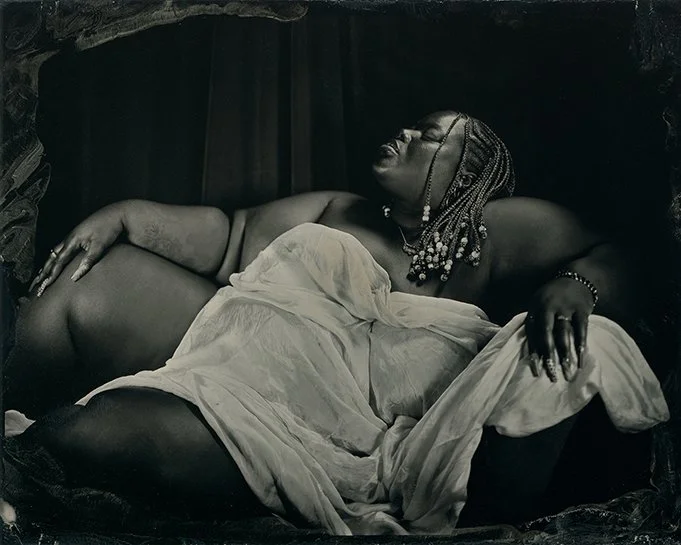 a tintype portrait of a person of color in repose, draped in white silk