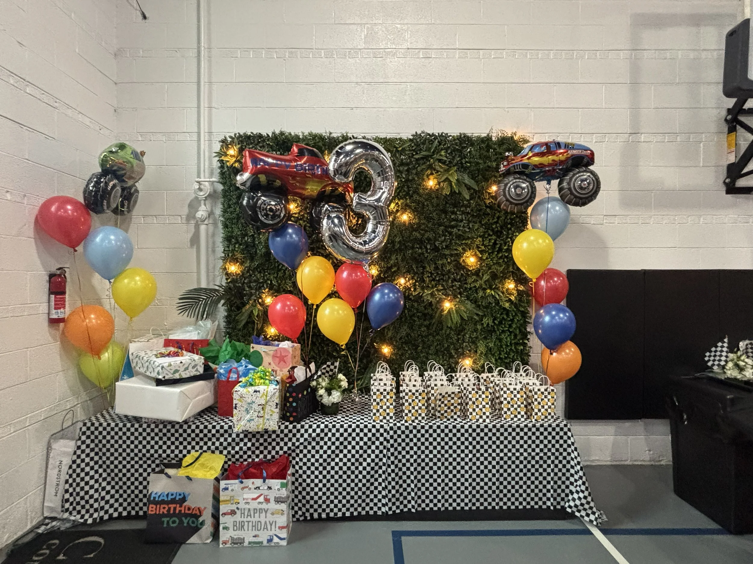 A birthday celebration setup with a greenery backdrop, balloons, gifts, and themed decorations.