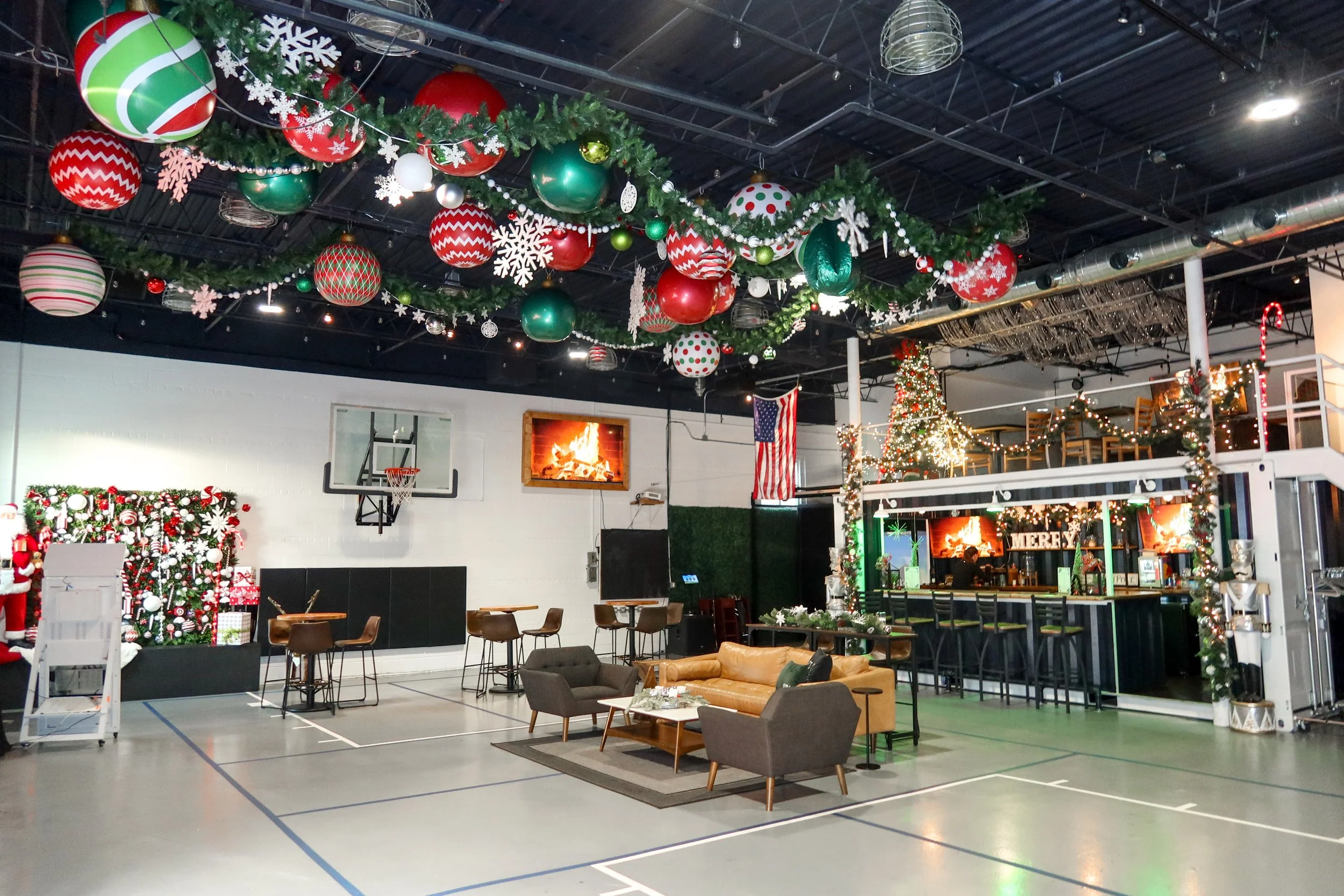 Indoor space decorated for Christmas with ornaments hanging from the ceiling, Christmas trees, and festive decorations.