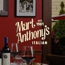 Sign for Mart Anthonys Italian restaurant, established in 1981, with two glasses of red wine in the foreground.