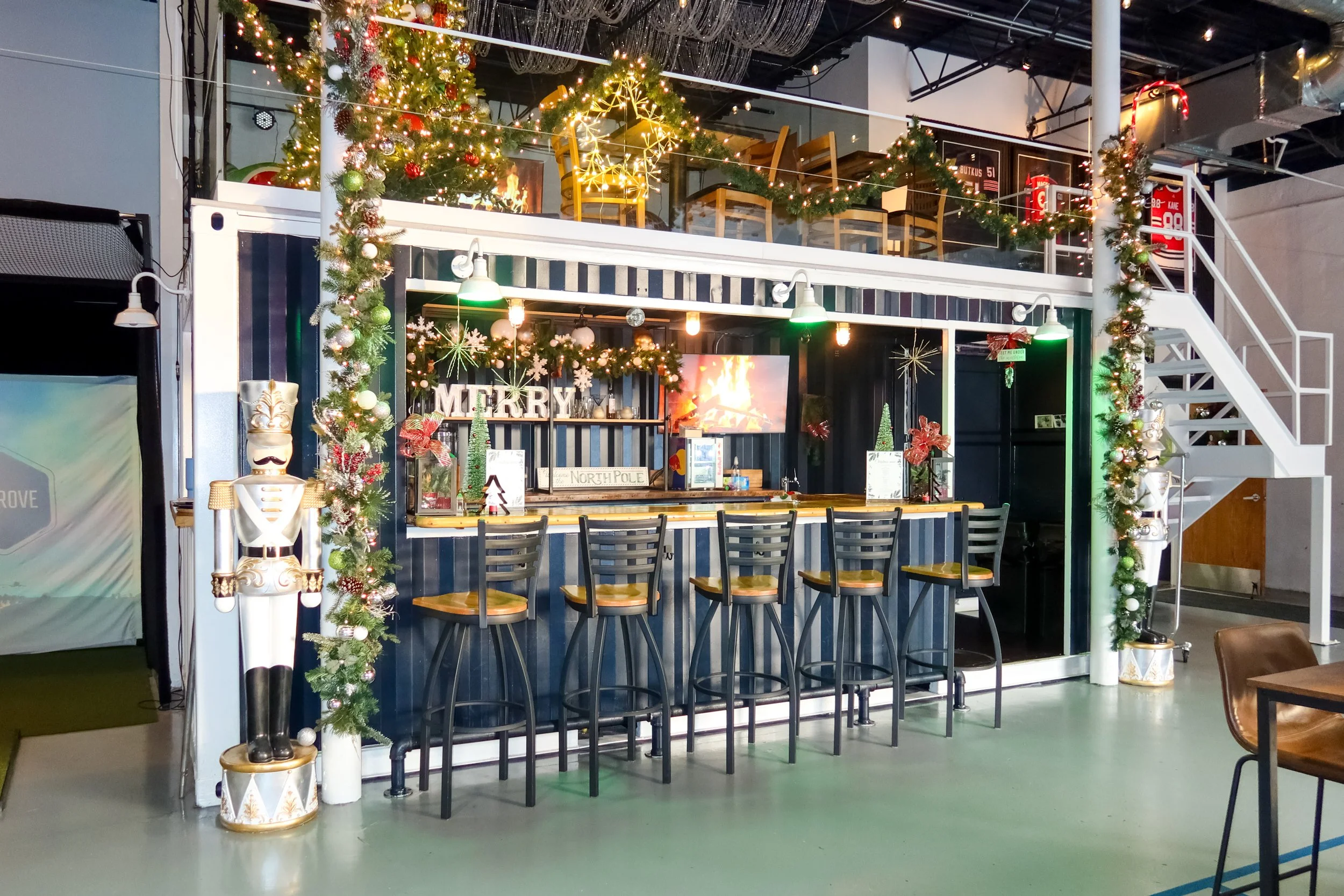 A decorated indoor space with a bar counter, Christmas trees, ornaments, and lights, indicating a festive holiday setting.