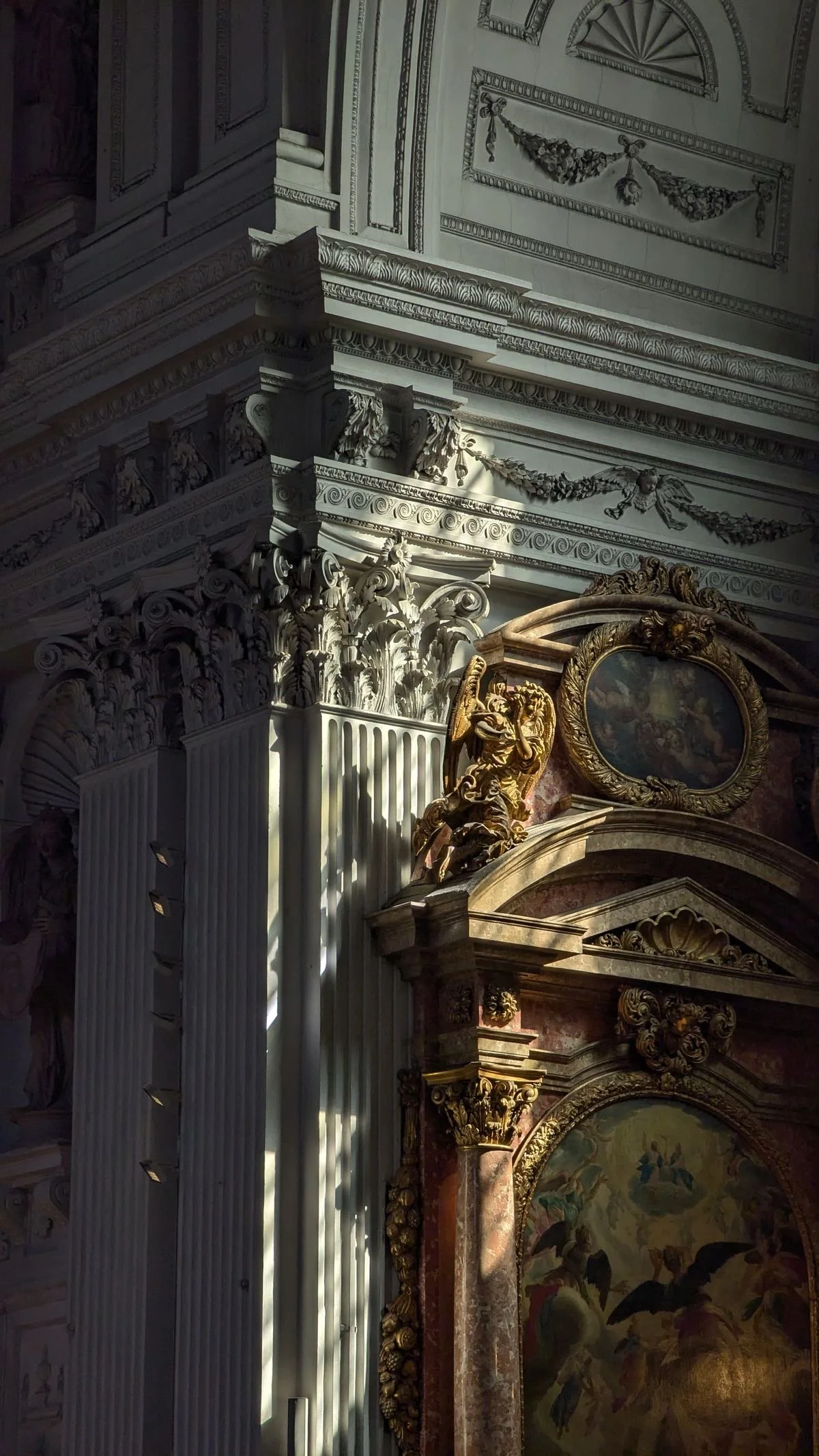 Interior of a grand historic building with ornate white and gold architectural details, including columns, intricate moldings, a painted ceiling, and a large mirror with a decorative frame.