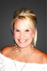 Portrait of a smiling blonde woman wearing pearl jewelry and an off-the-shoulder white dress