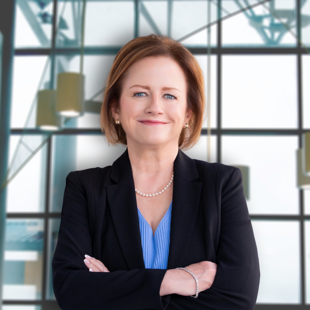 Professional woman smiling with arms crossed in front of modern glass building.