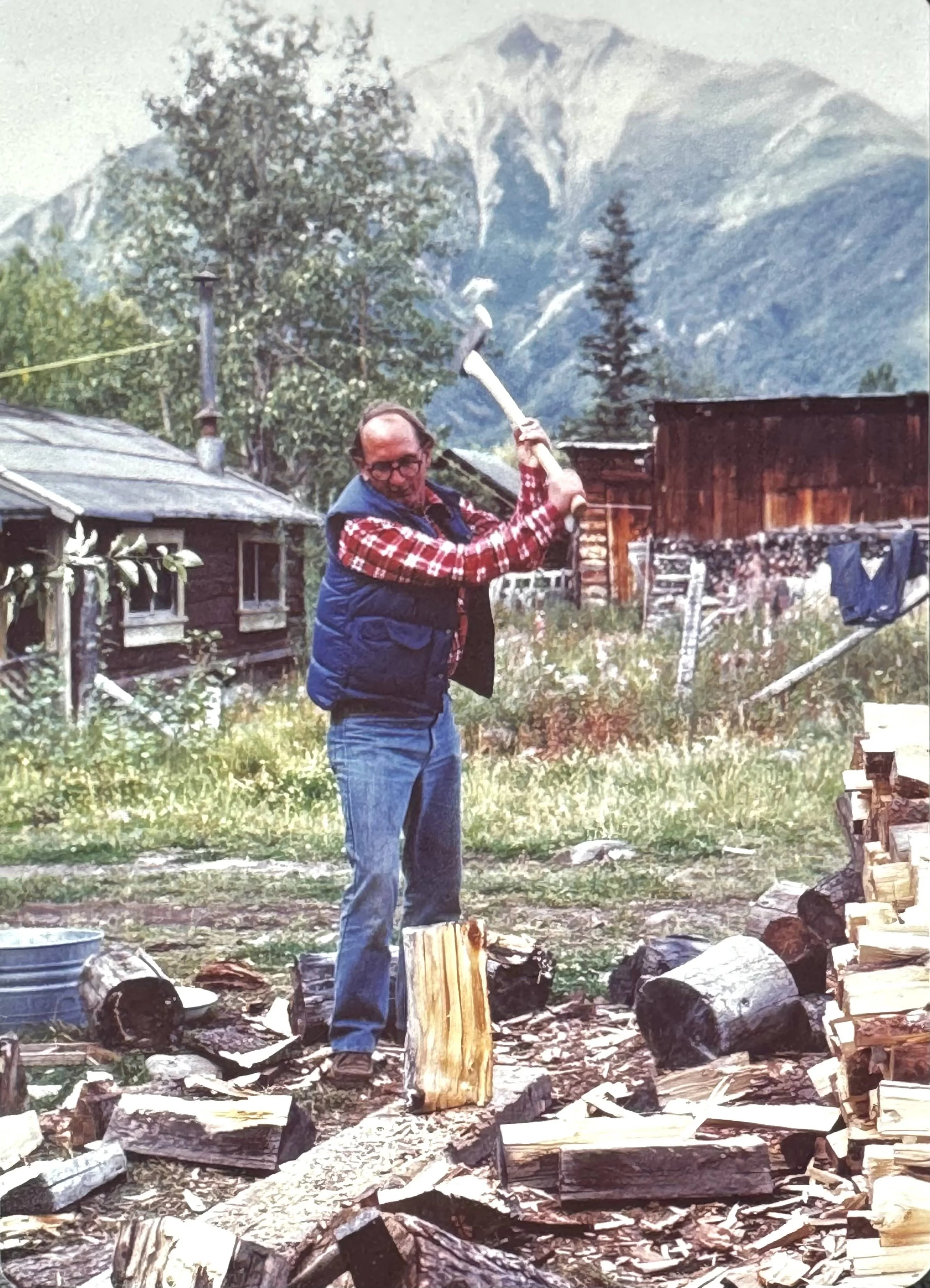 Dr. Richard Cooley splitting firewood in front of the Old Hardware Store in McCarthy, late 1970s