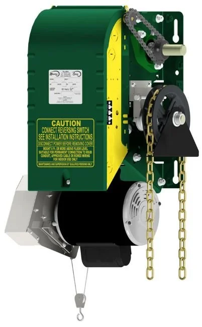 Industrial garage door operator with chains, gears, control panel, and warning labels.