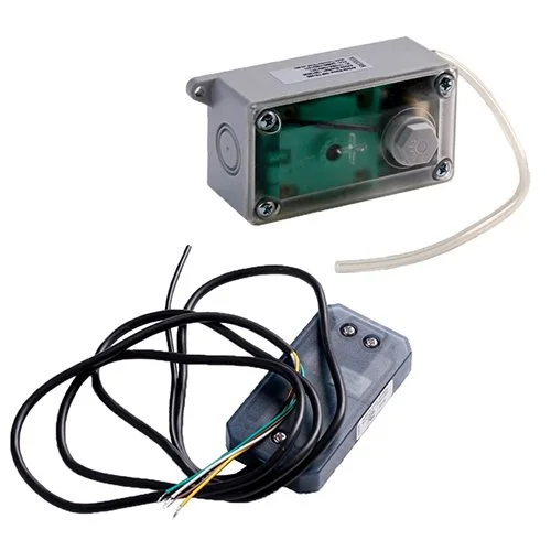 A gray electrical box with a connected tube, a gray device with black and yellow wires, and a tangled black power cord.